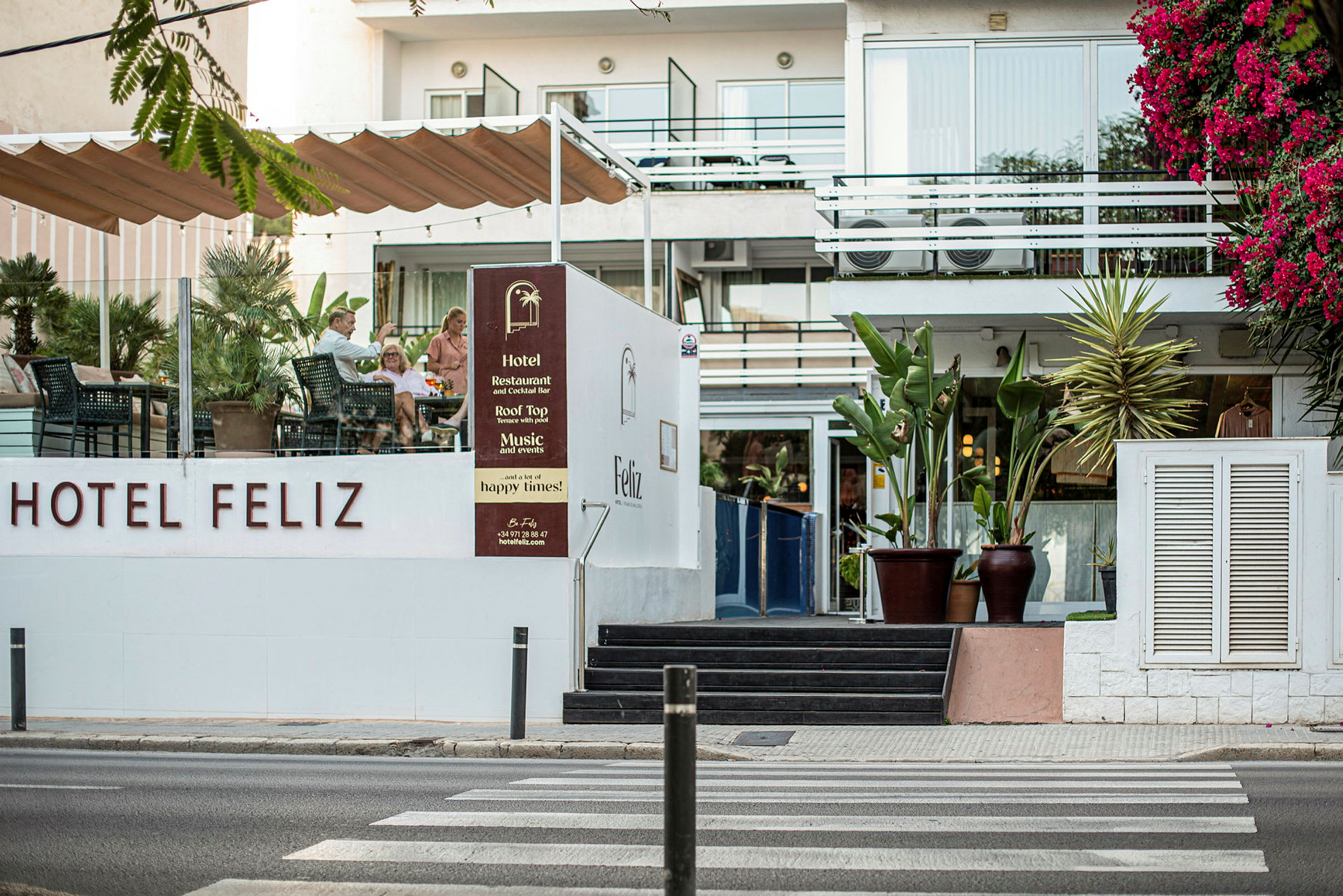 Hotel Feliz ulkoterassilla ja kukkivalla kasvillisuudella. (Tekoälyn luoma teksti)