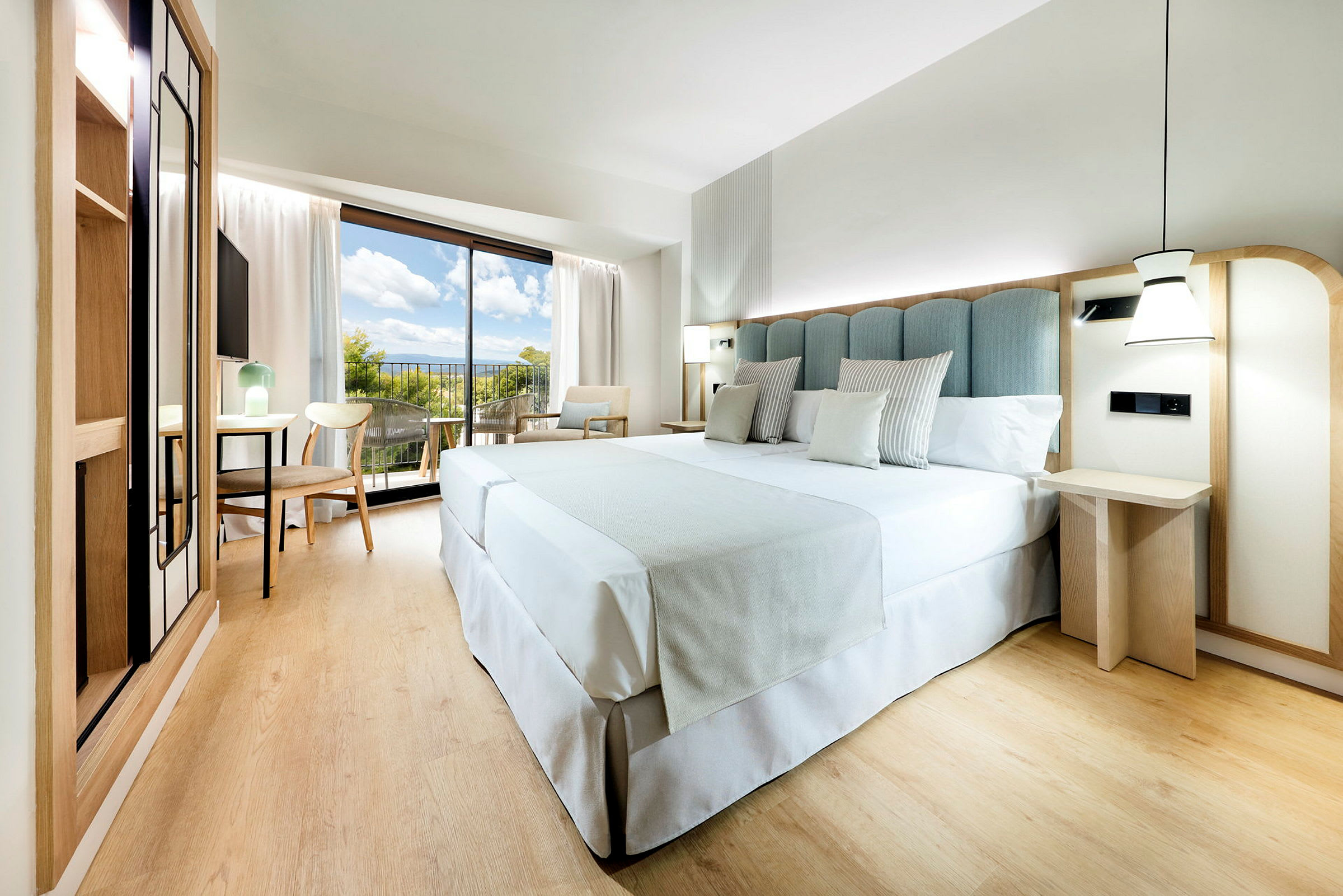 Moderni hotellihuone, jossa on suuri sänky, puuhuonekaluja ja parveke näköalalla. (Tekoälyn luoma teksti)