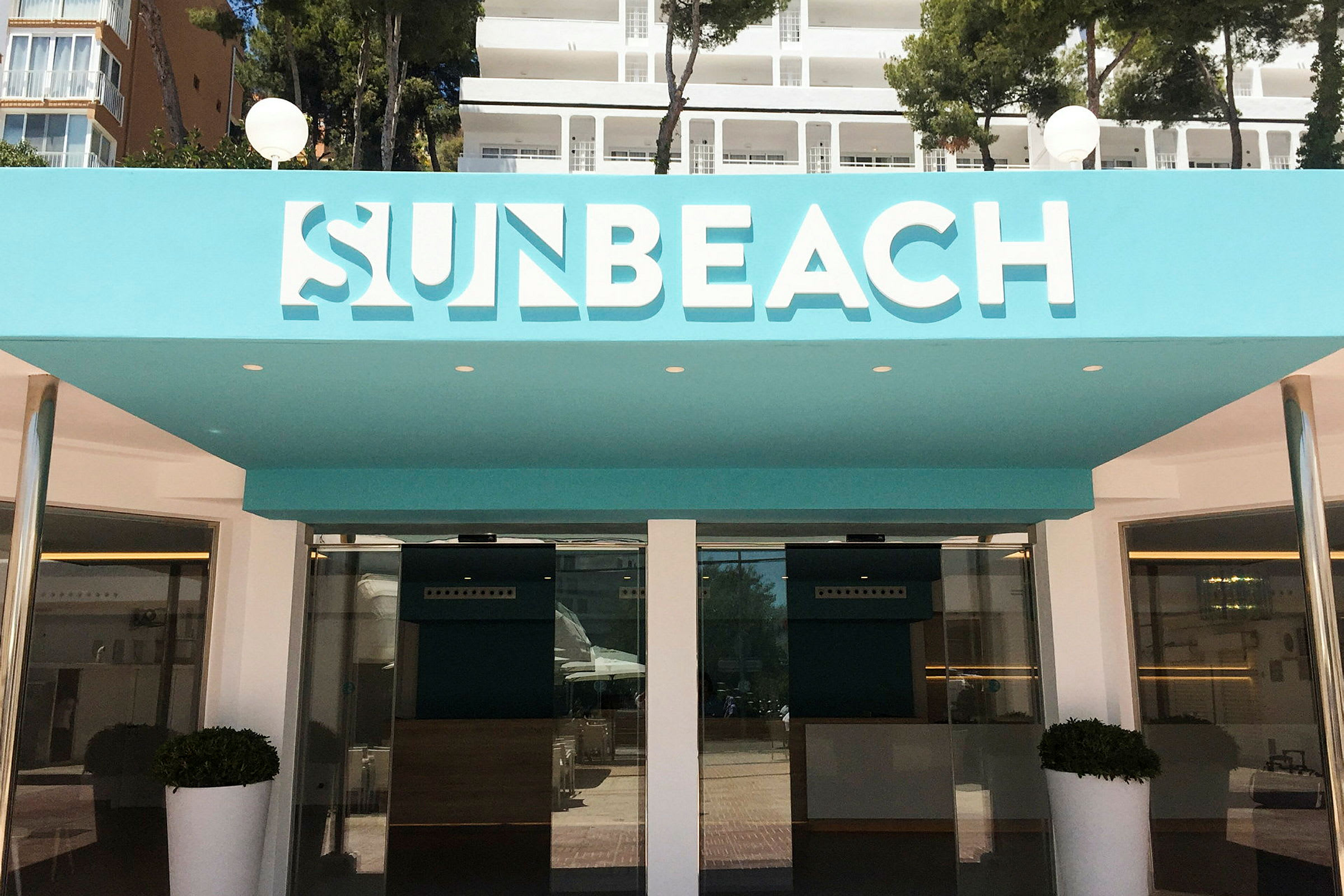 Sun Beach -hotellin sisäänkäynti turkooseilla yksityiskohdilla. (Tekoälyn luoma teksti)