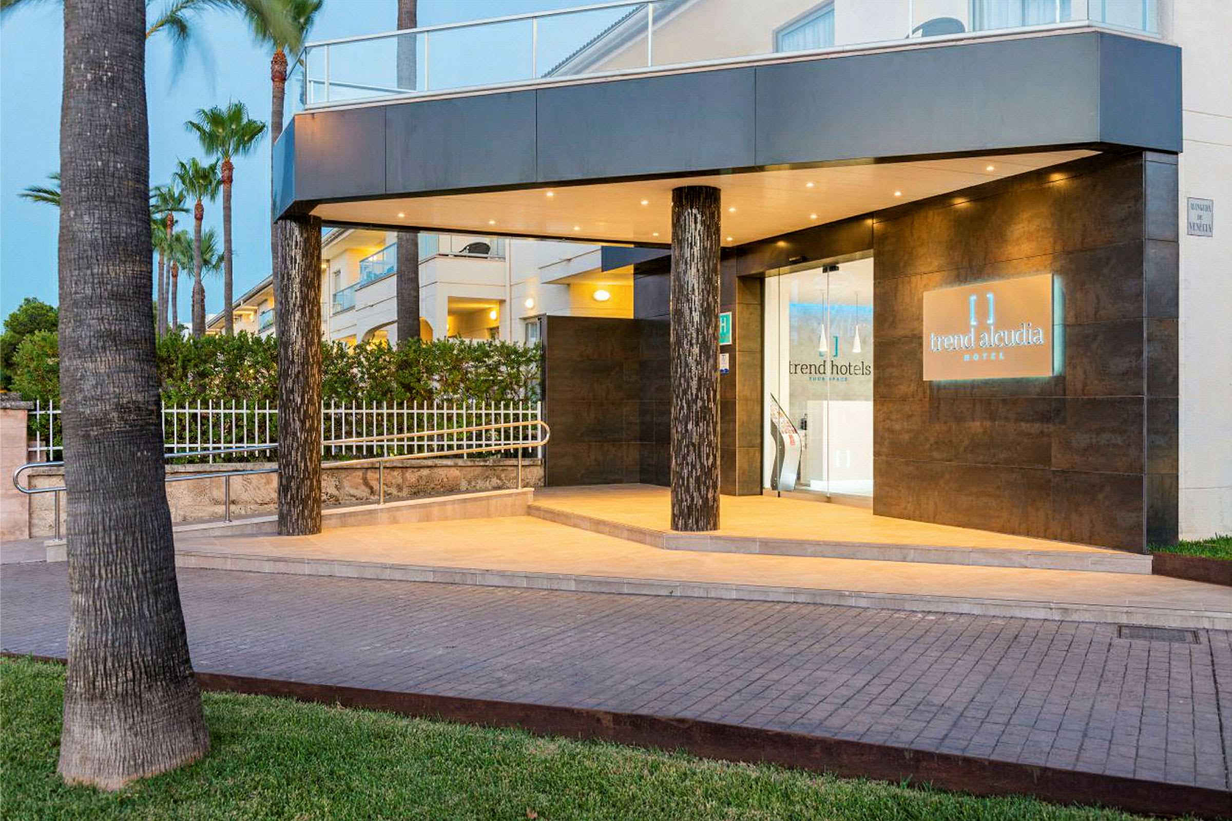 Hotellin sisäänkäynti valaistuksella ja nimellä 'Trend Alcudia Hotel' kyltissä. (Tekoälyn luoma teksti)