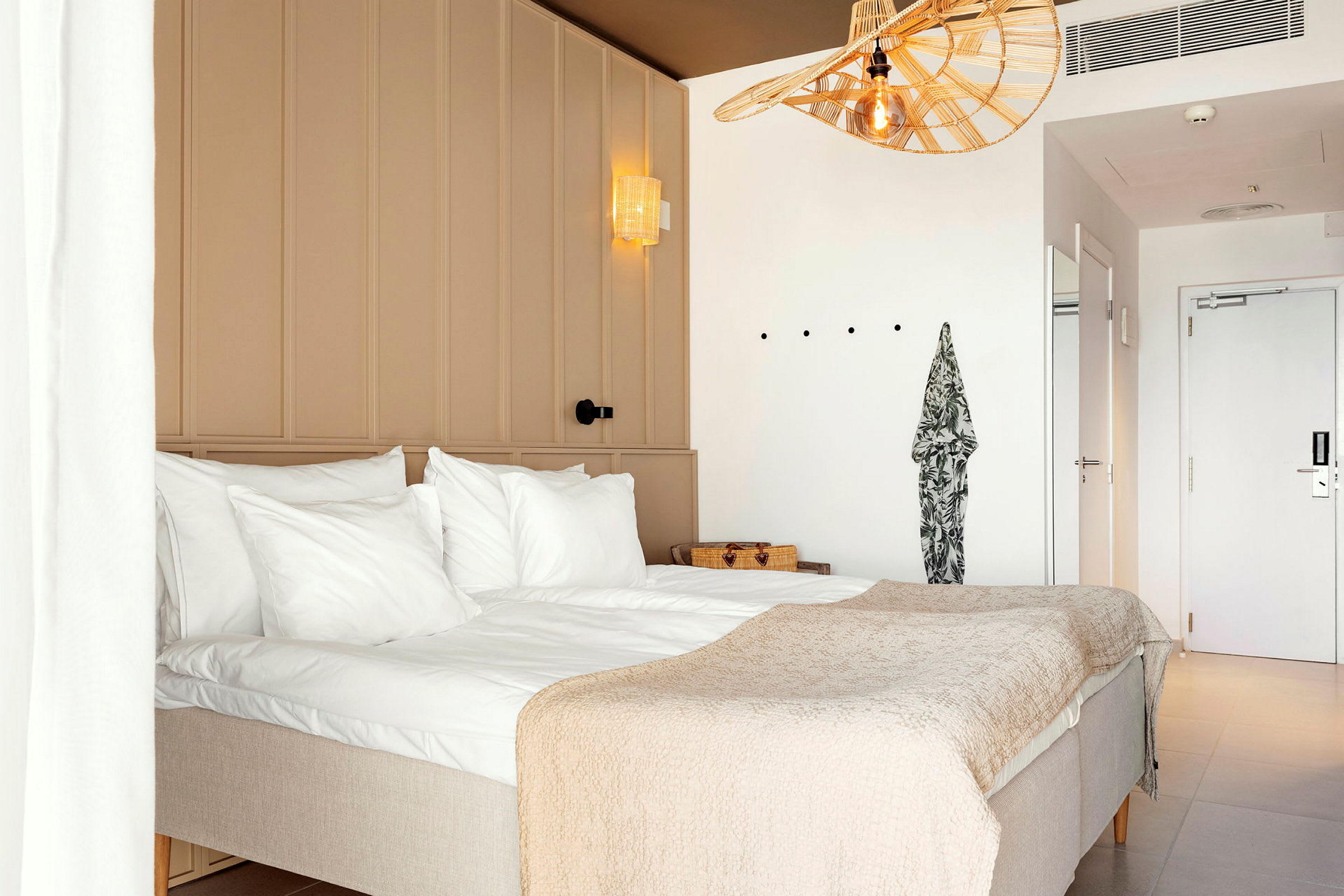 Hotellihuone, jossa on parisänky, valkoiset seinät ja vaalea sisustus. (Tekoälyn luoma teksti)