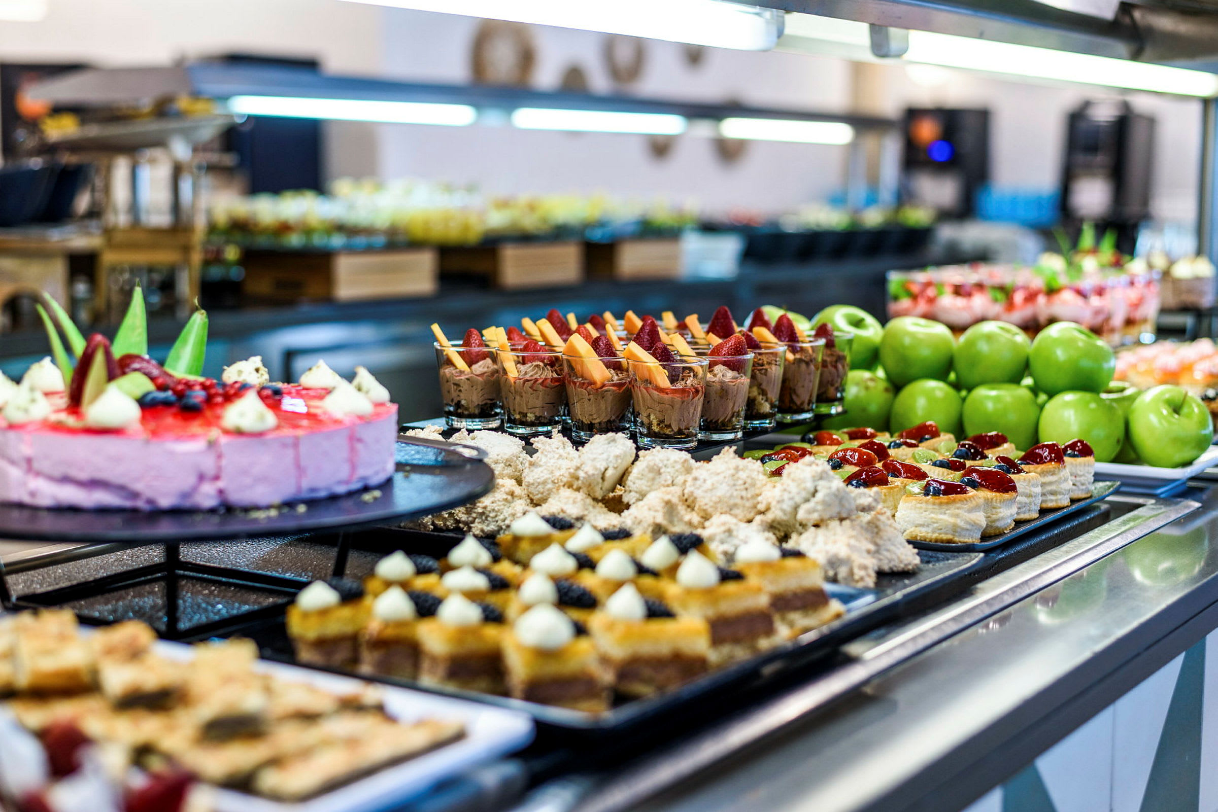 Buffet, jossa on erilaisia jälkiruokia, kakkuja ja vihreitä omenoita. (Tekoälyn luoma teksti)
