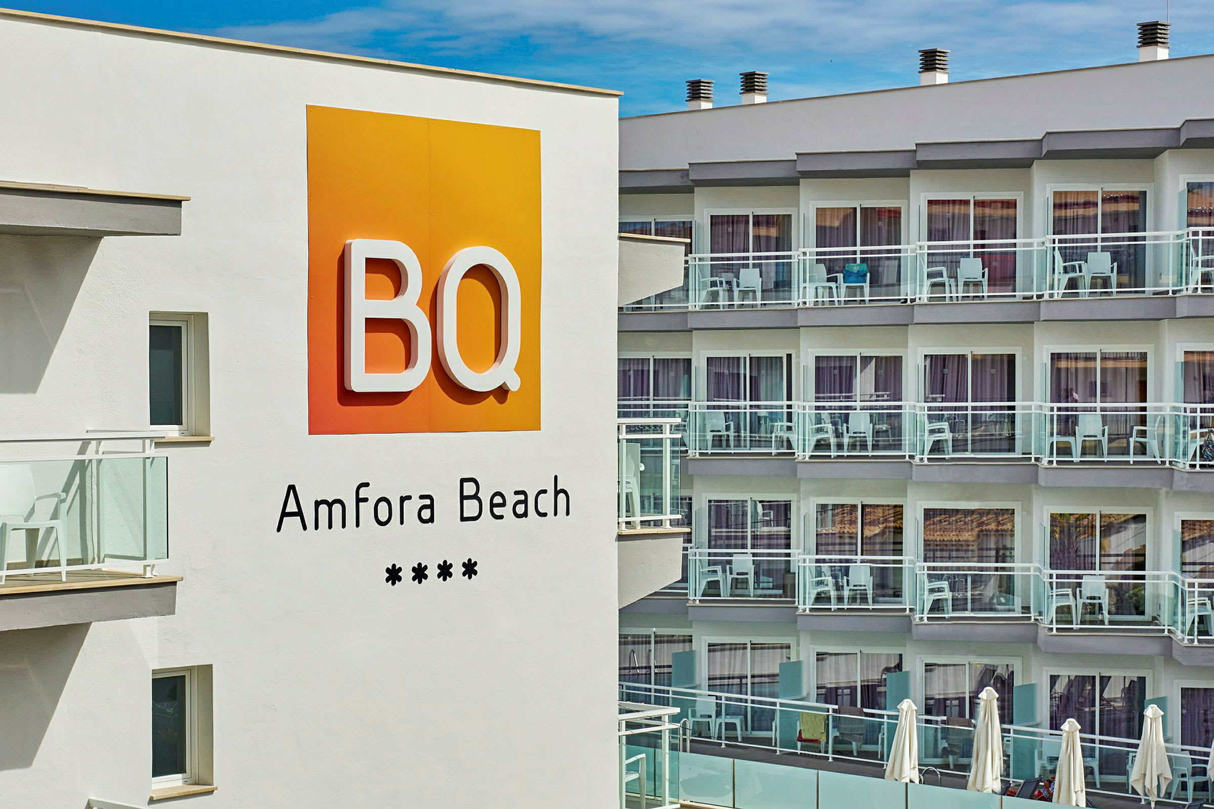 Hotellin kyltti, jossa lukee "BQ Amfora Beach", rakennuksen parvekkeiden edessä. (Tekoälyn luoma teksti)