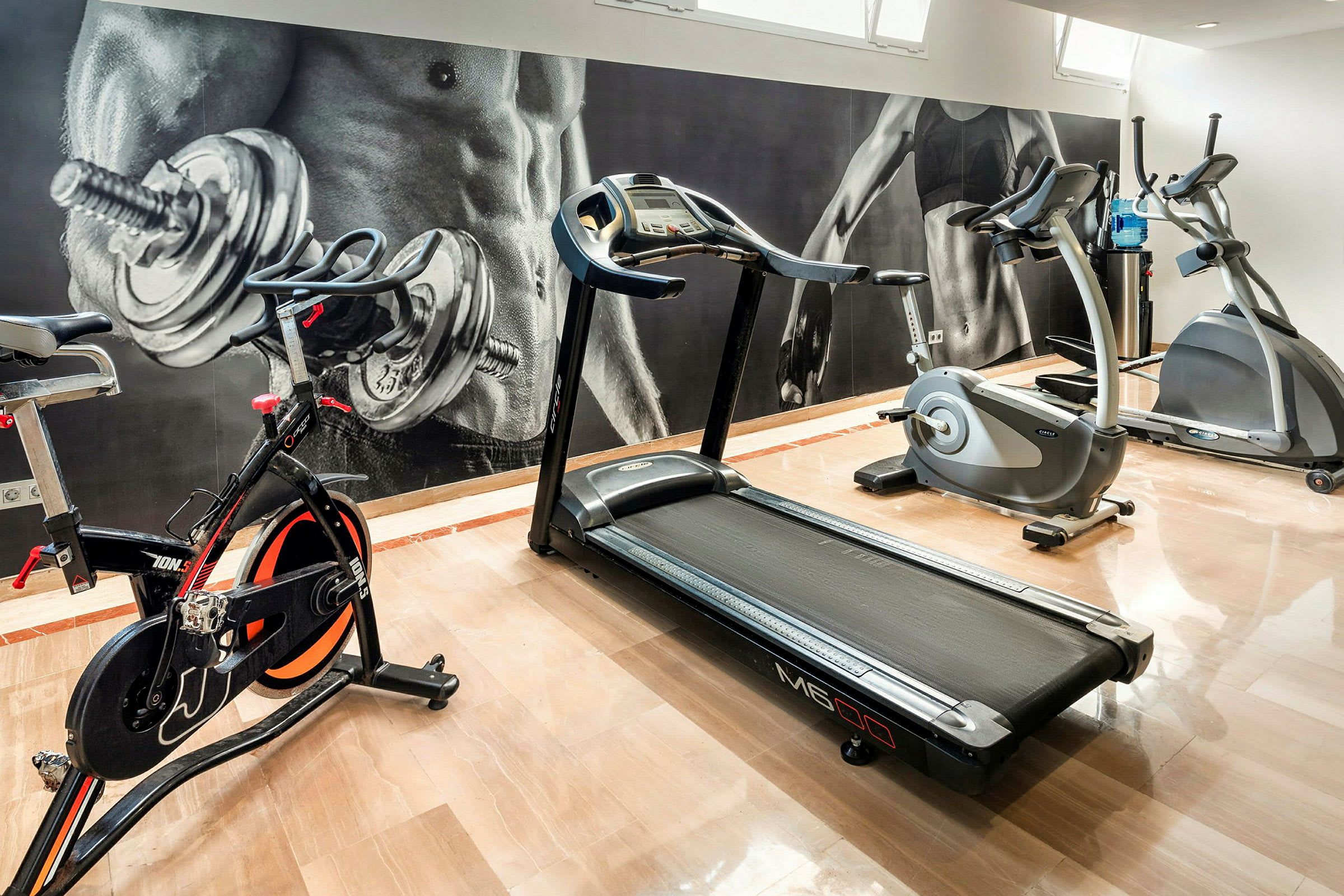 Kuntosali, jossa on kuntopyörä, juoksumatto ja elliptinen cross-trainer. (Tekoälyn luoma teksti)
