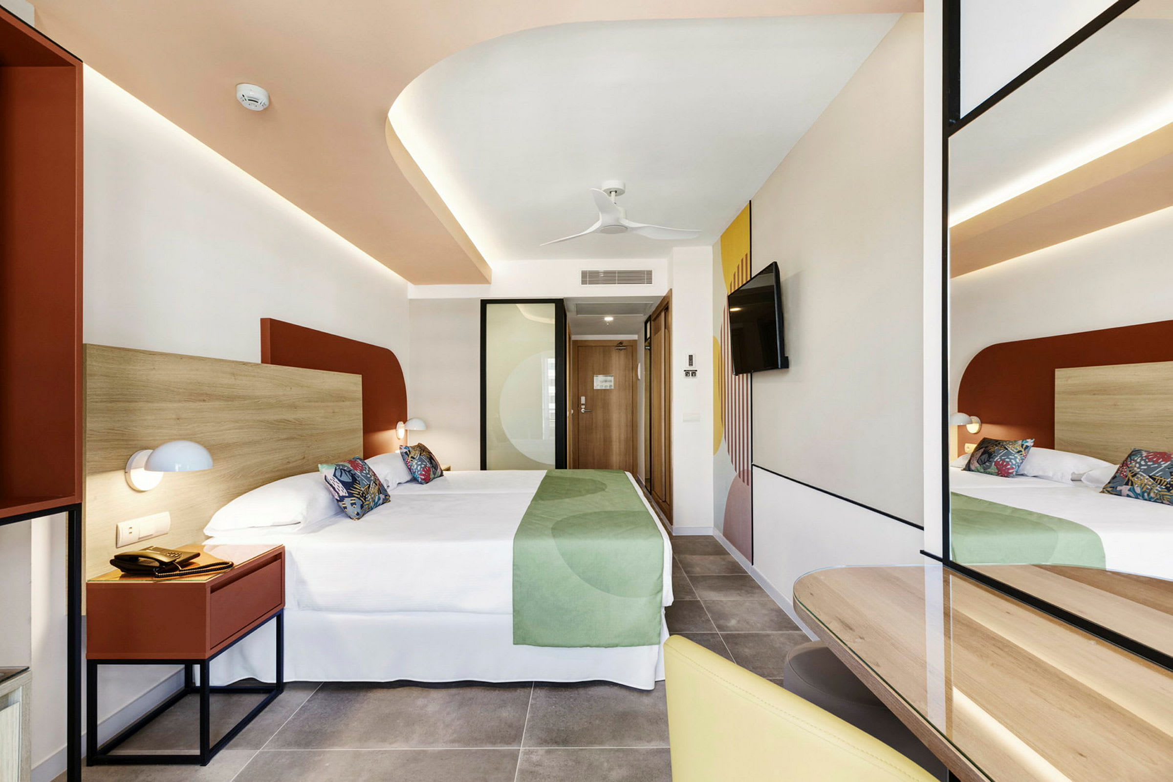Hotellihuone, jossa on moderni sisustus, parivuode ja peili. (Tekoälyn luoma teksti)