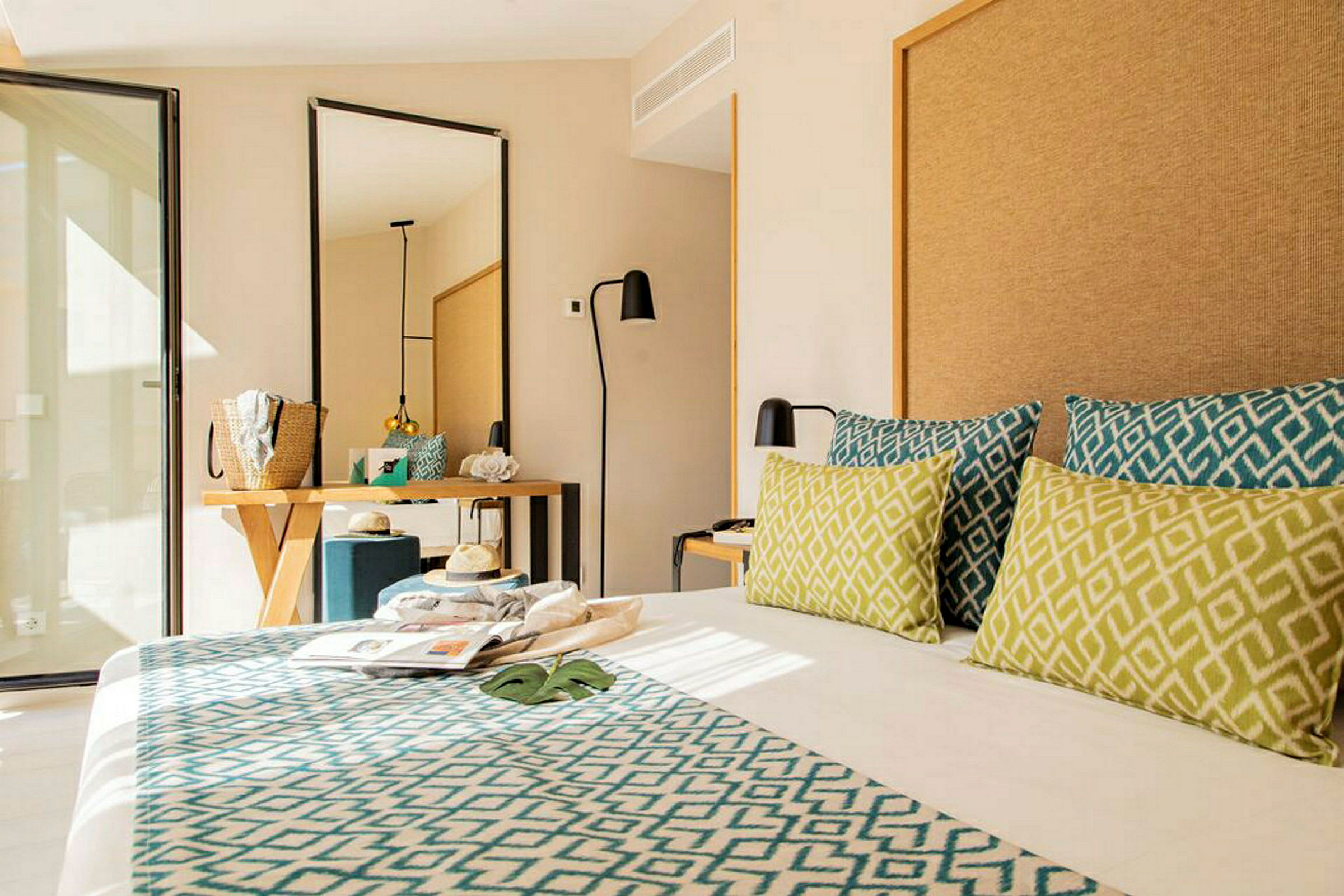 Hotellihuone modernilla sisustuksella, sänky koristeellisilla tyynyillä, peili ja työpöytä. (Tekoälyn luoma teksti)