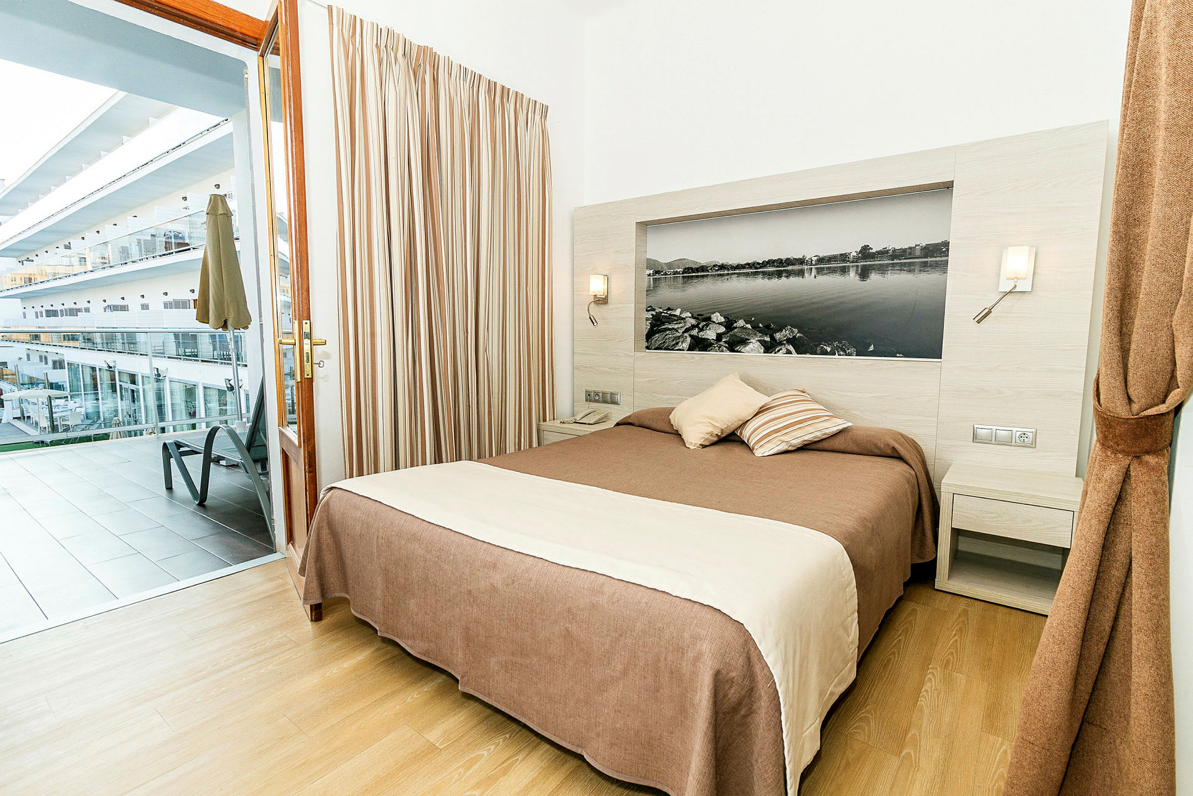 Hotellihuone, jossa on parivuode ja pääsy parvekkeelle, jolta on näkymä muihin rakennuksiin. (Tekoälyn luoma teksti)
