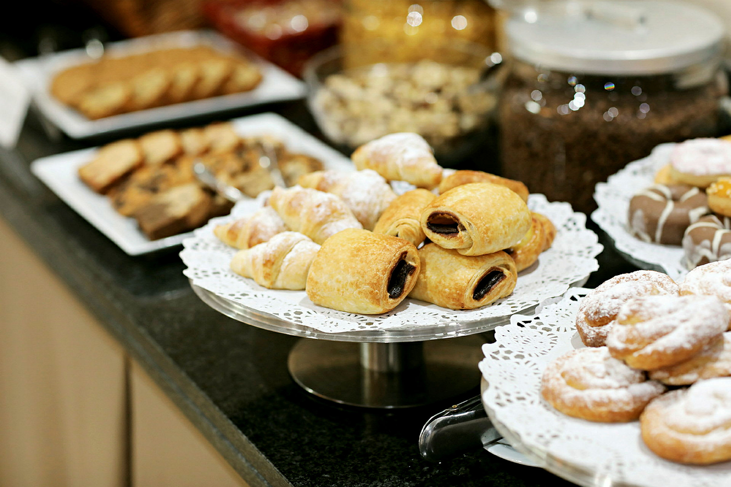 Valikoima leivonnaisia lautasilla, mukaan lukien croissanteja ja muita makeita leivonnaisia. (Tekoälyn luoma teksti)