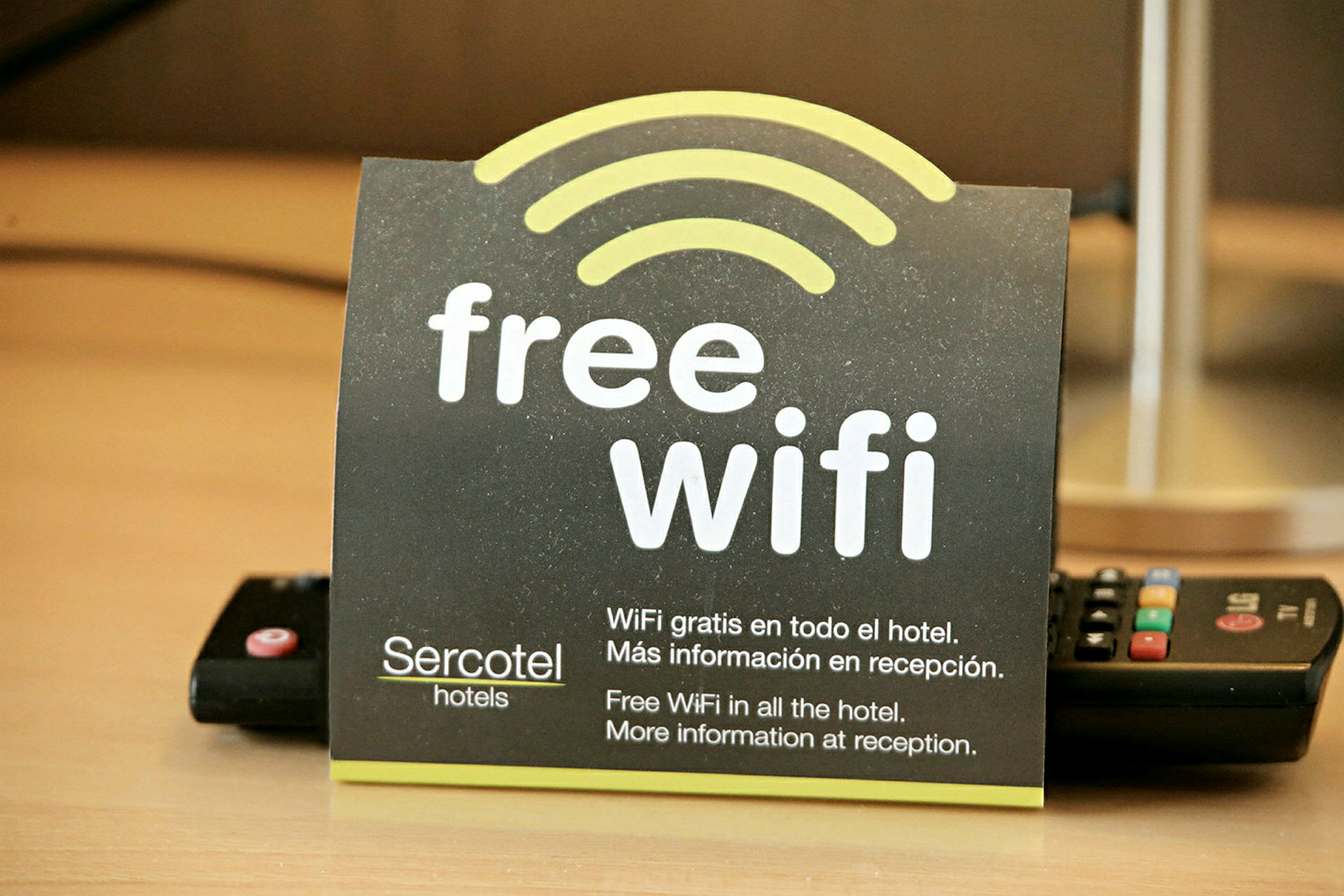 Kortti, joka ilmoittaa hotellin ilmaisesta Wi-Fi:stä englanniksi ja espanjaksi. (Tekoälyn luoma teksti)