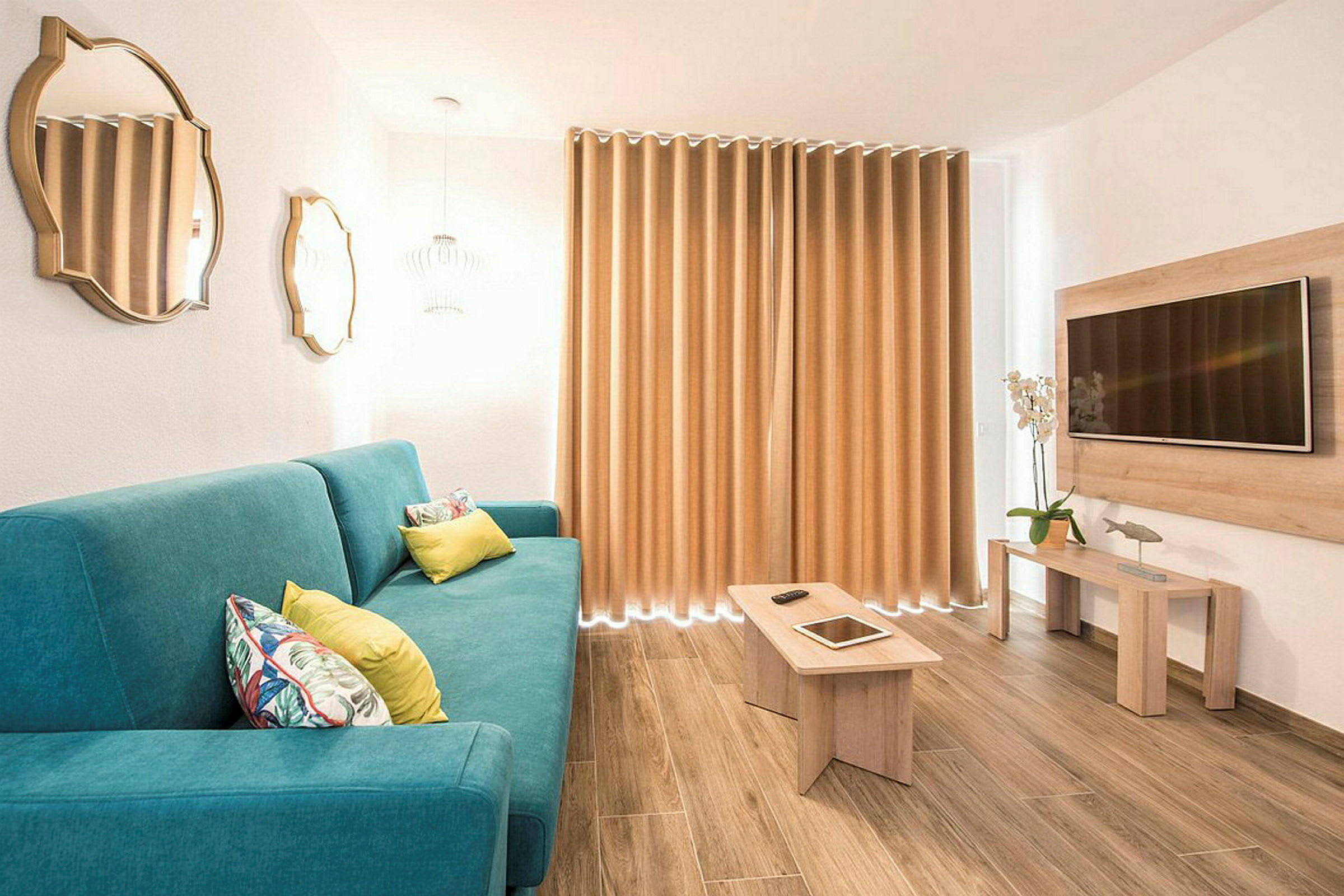 Moderni olohuone, jossa sininen sohva, puinen pöytä ja seinään kiinnitetty televisio. (Tekoälyn luoma teksti)