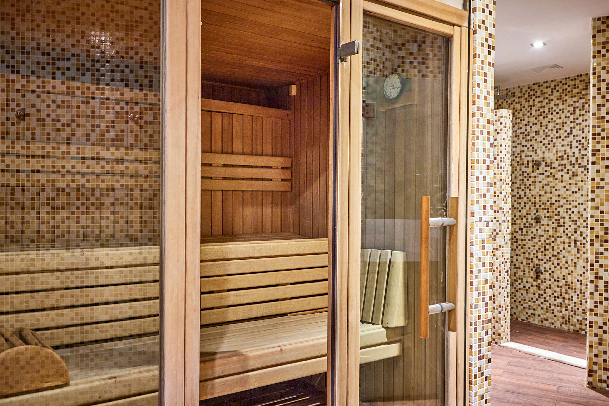 Puupaneeleilla varustettu sauna, jossa lasipaneelit ja laatoitetut seinät ulkopuolella. (Tekoälyn luoma teksti)
