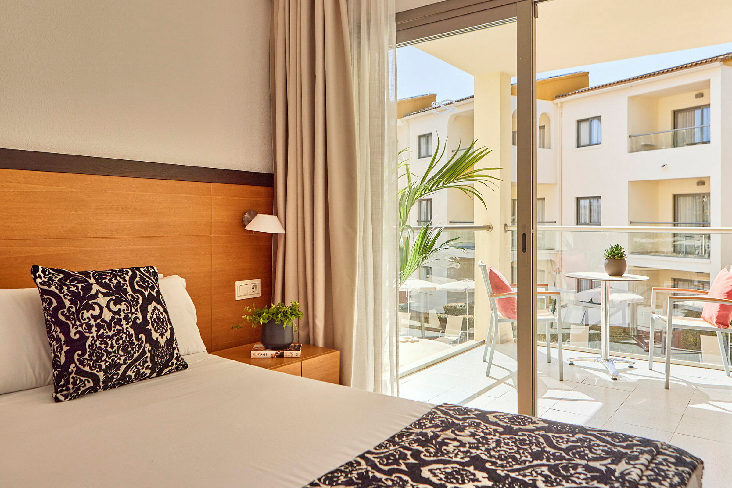 Hotellihuone, jossa sänky ja parveke kalusteilla. (Tekoälyn luoma teksti)