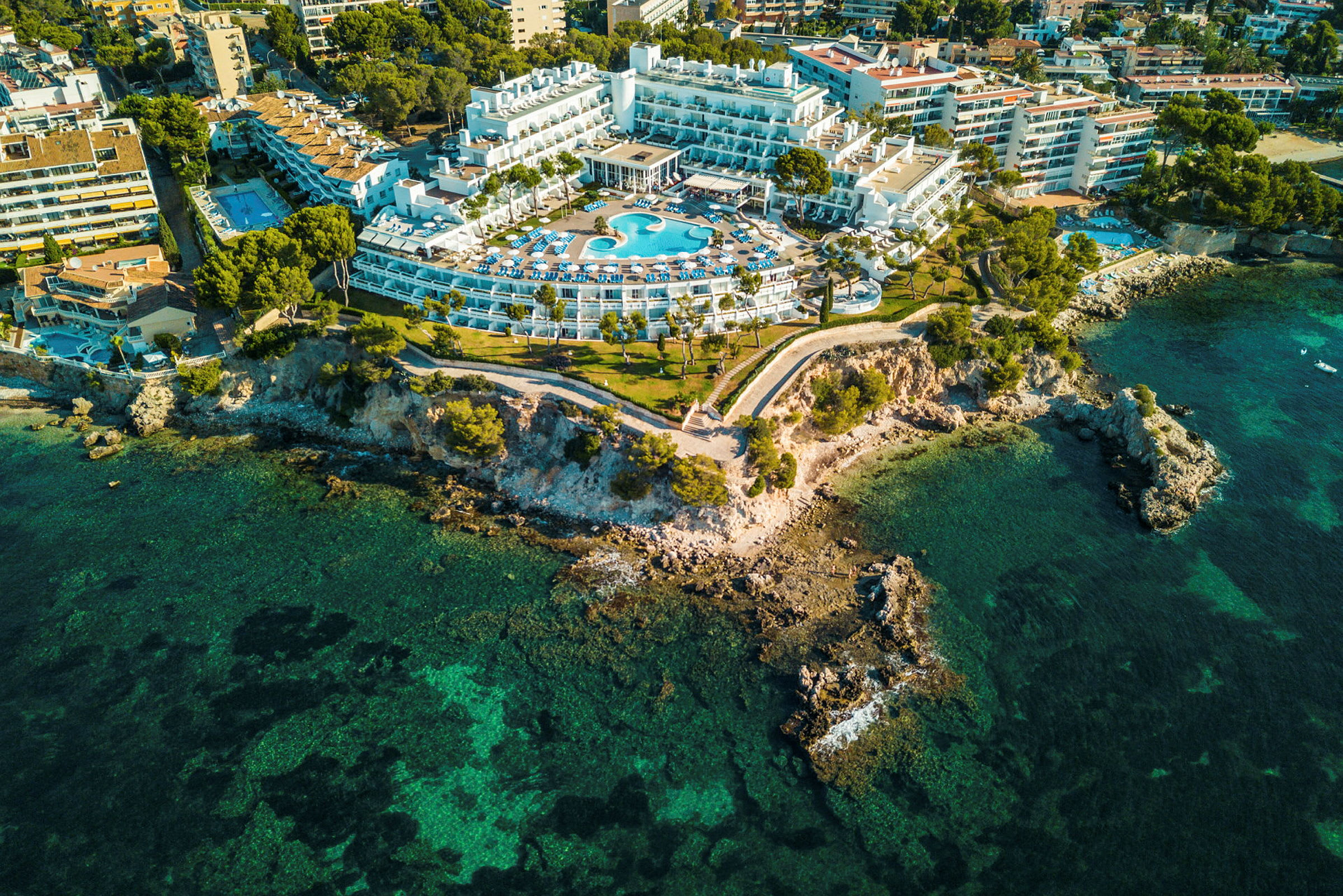 Ilmakuva hotellista, jossa on uima-allas, sijaitsee kallioisella rannikolla. (Tekoälyn luoma teksti)