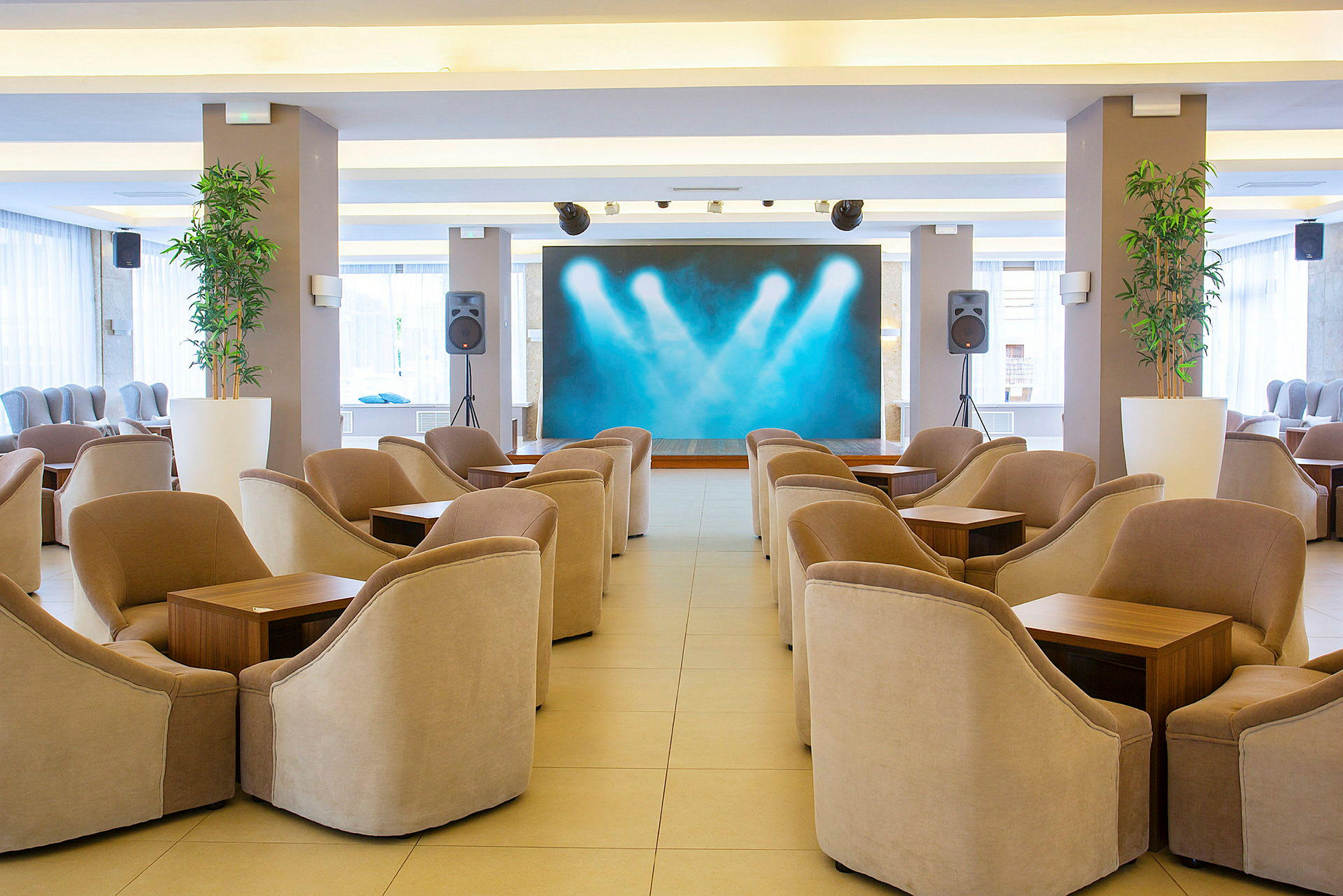 Lounge, jossa on tuoleja, pöytiä ja valaistu lava. (Tekoälyn luoma teksti)