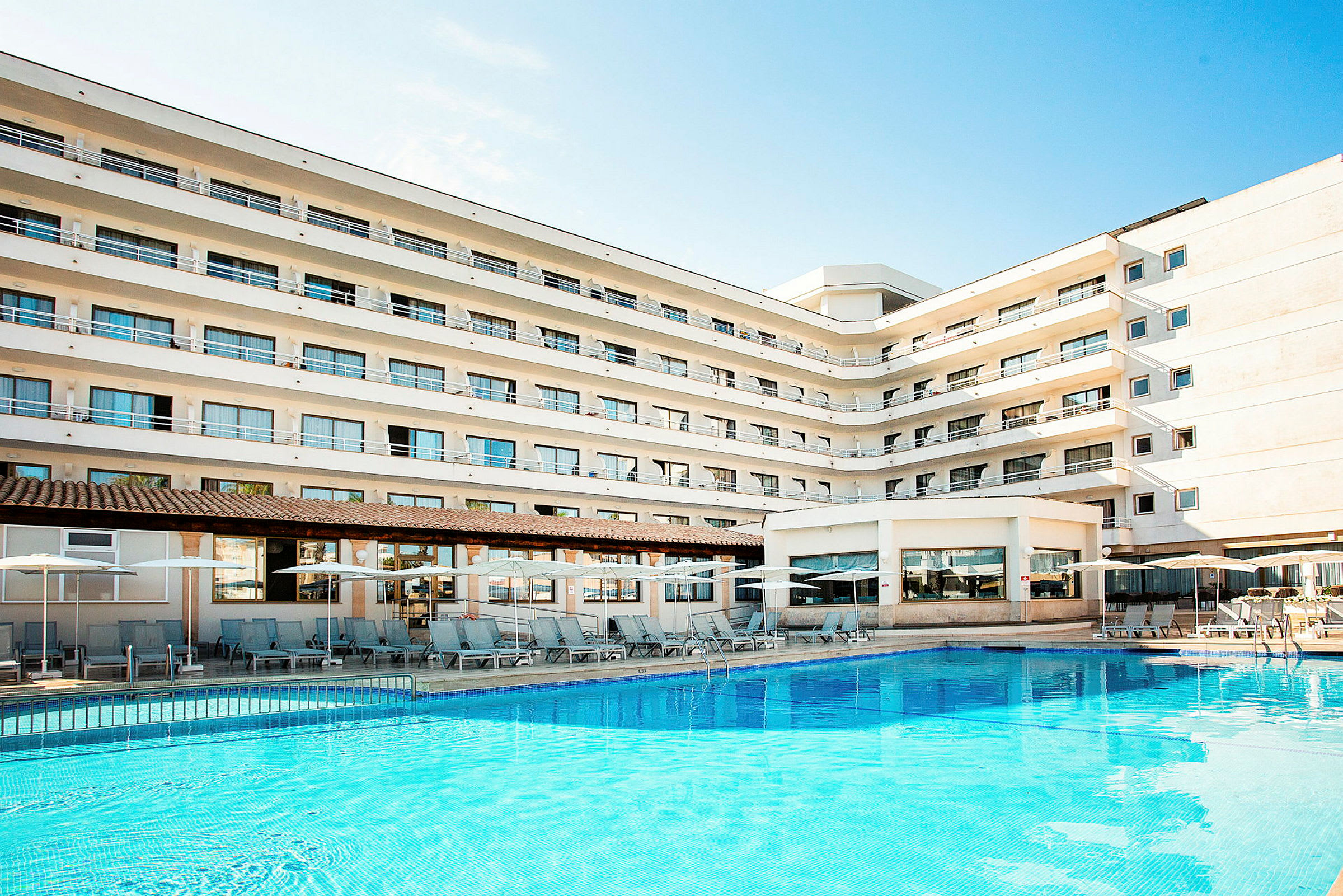 Kuva hotellista, jossa on useita kerroksia ja uima-allas rakennuksen edessä. (Tekoälyn luoma teksti)