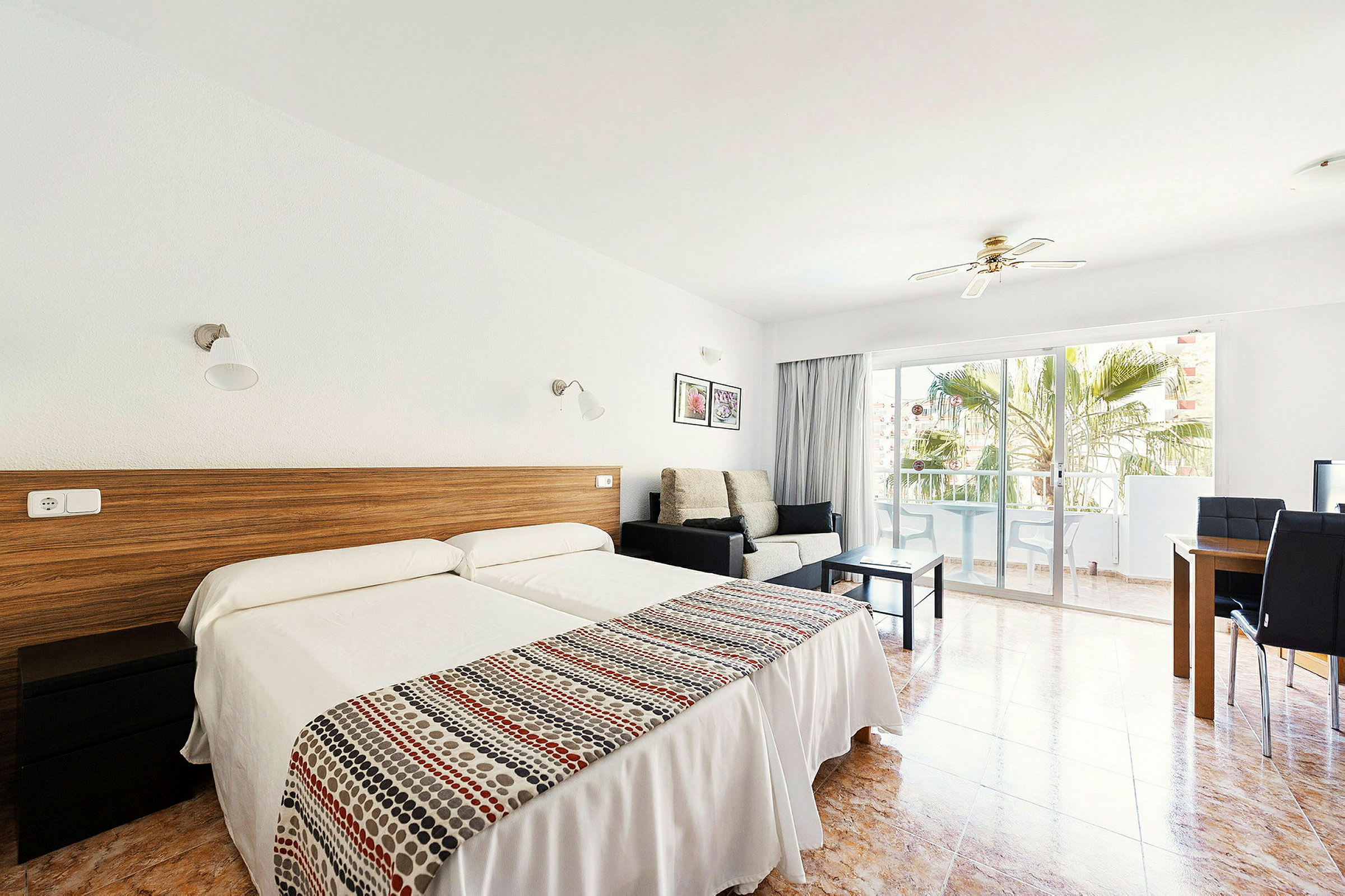 Hotellihuone, jossa kaksi yhden hengen vuodetta, istuinalue ja parveke. (Tekoälyn luoma teksti)