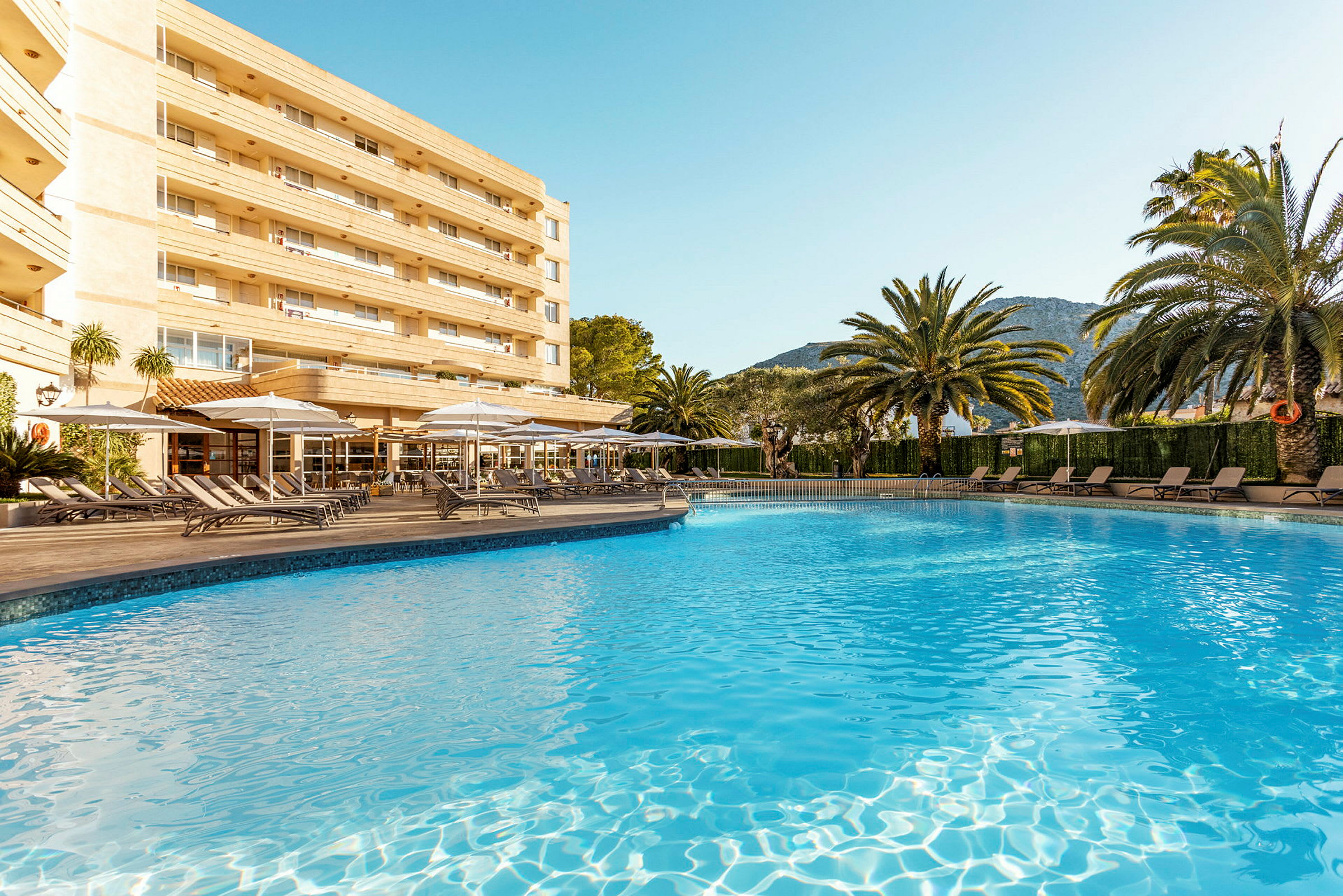 Kuva uima-altaasta, aurinkotuoleista ja hotellista taustalla. (Tekoälyn luoma teksti)