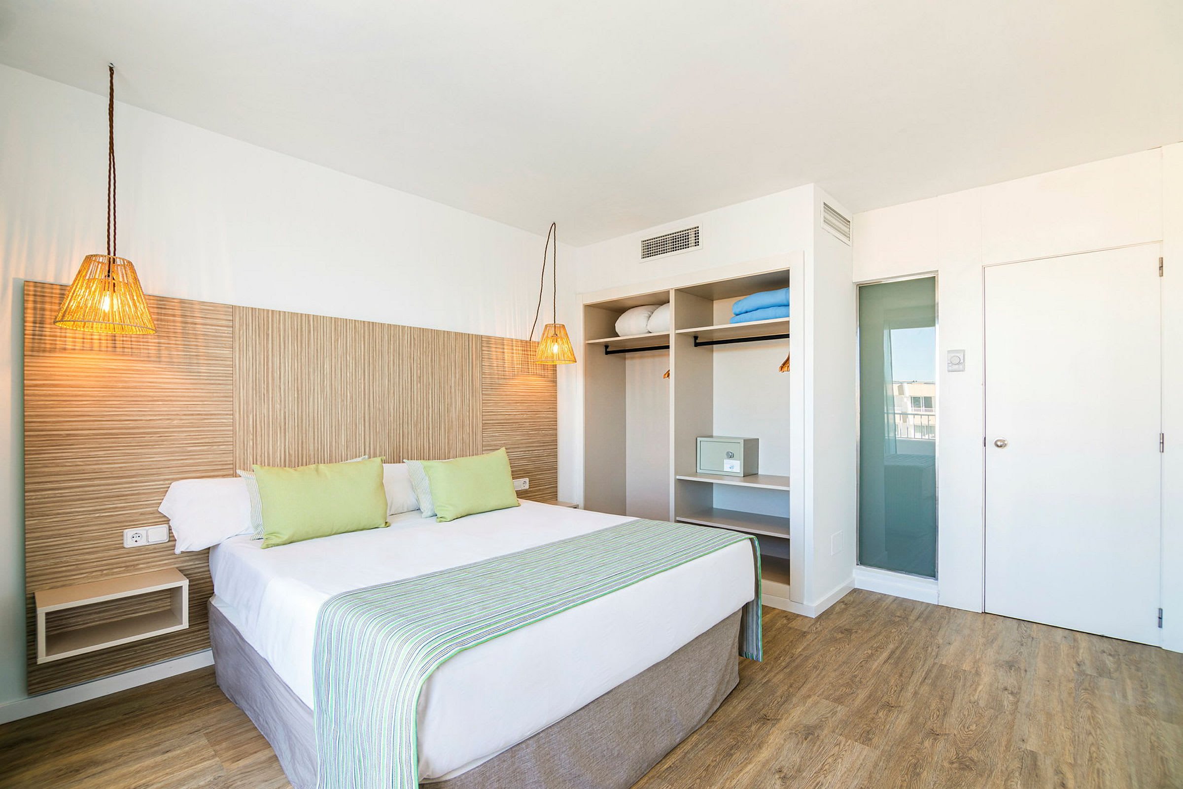 Hotellihuone, jossa on parivuode, vaaleat huonekalut ja avoin vaatekaappi. (Tekoälyn luoma teksti)