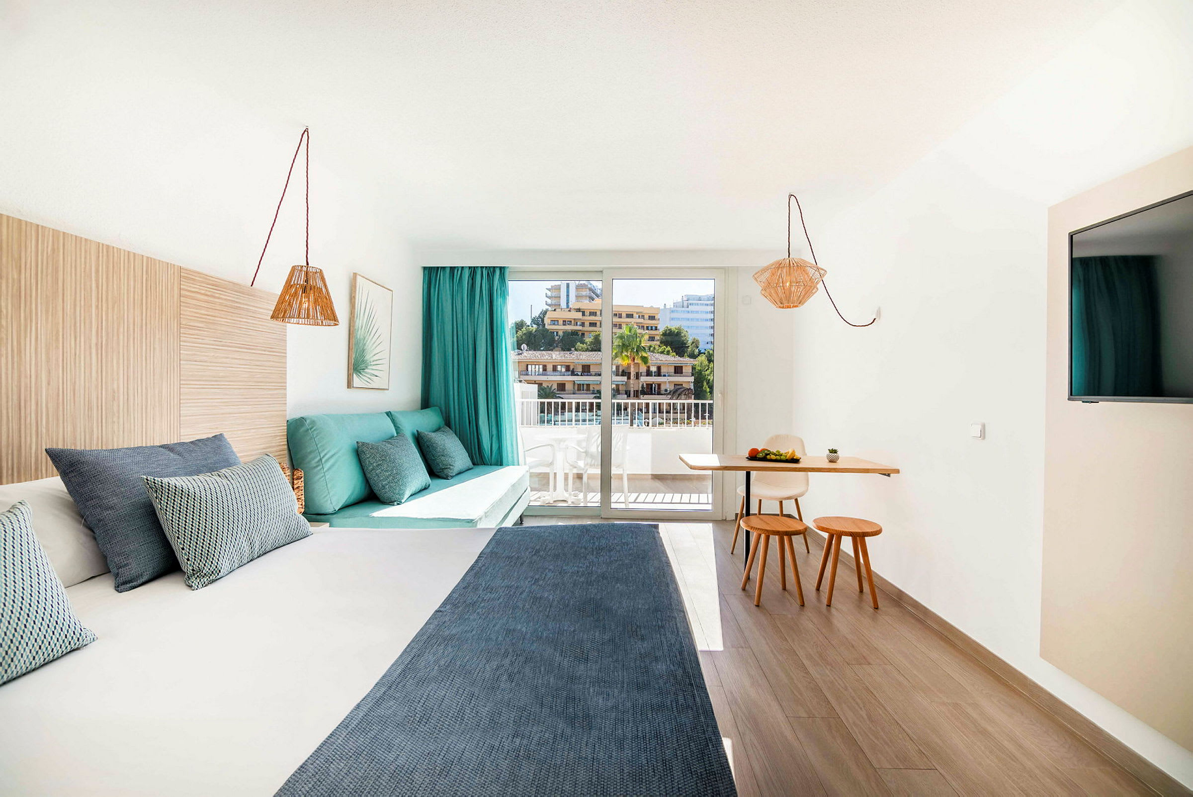 Moderni hotellihuone, jossa sänky, oleskelutila ja pieni ruokailutila suurella ikkunalla. (Tekoälyn luoma teksti)