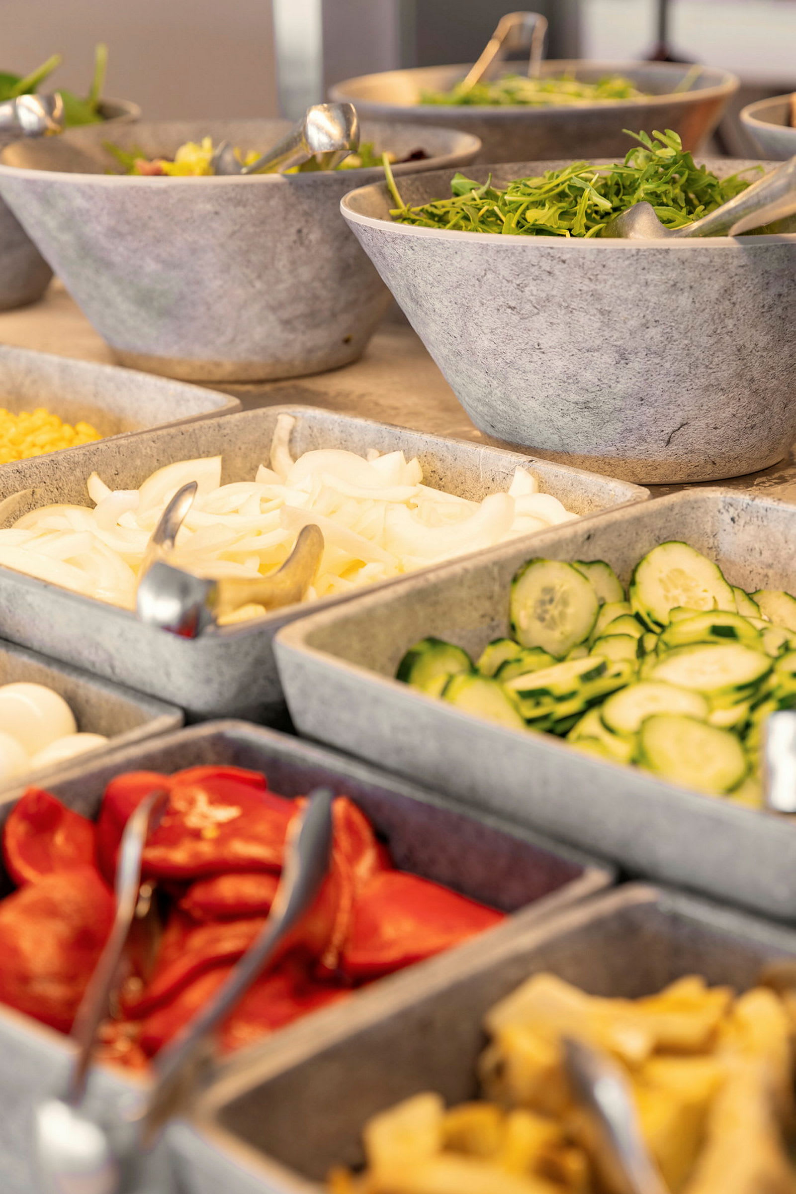 Salaattibuffet, jossa on erilaisia vihanneksia ja lisukkeita kulhoissa. (Tekoälyn luoma teksti)