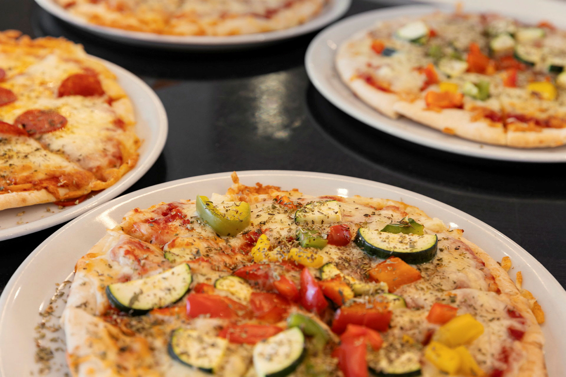 Neljä pizzaa eri täytteillä lautasilla. (Tekoälyn luoma teksti)