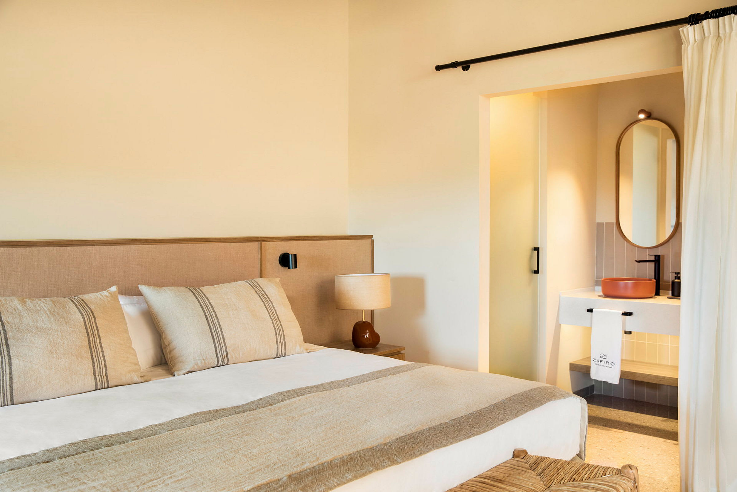 Hotellihuone, jossa on sänky, lamppu ja näkyvä osa kylpyhuonetta. (Tekoälyn luoma teksti)