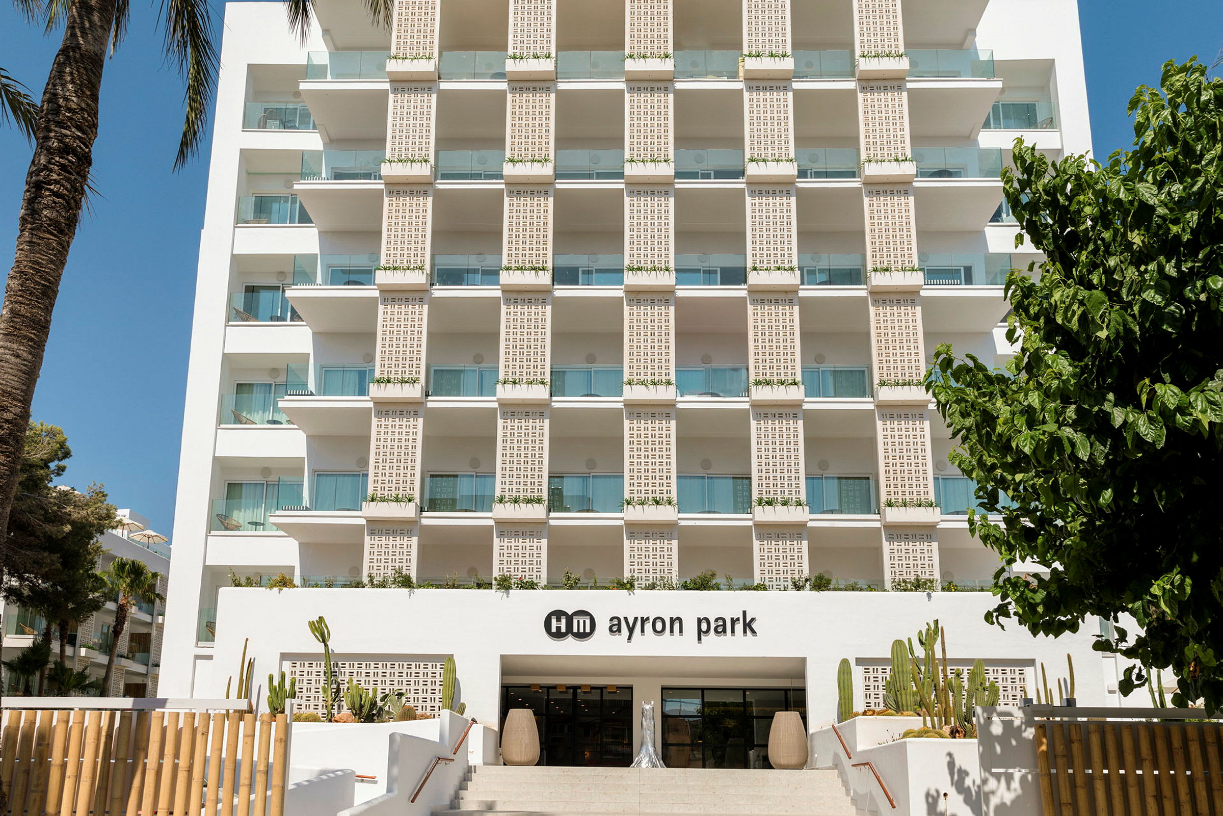Hotellijulkisivu parvekkeineen ja hm ayron park -sisäänkäynti, koristeltu kaktuksilla. (Tekoälyn luoma teksti)
