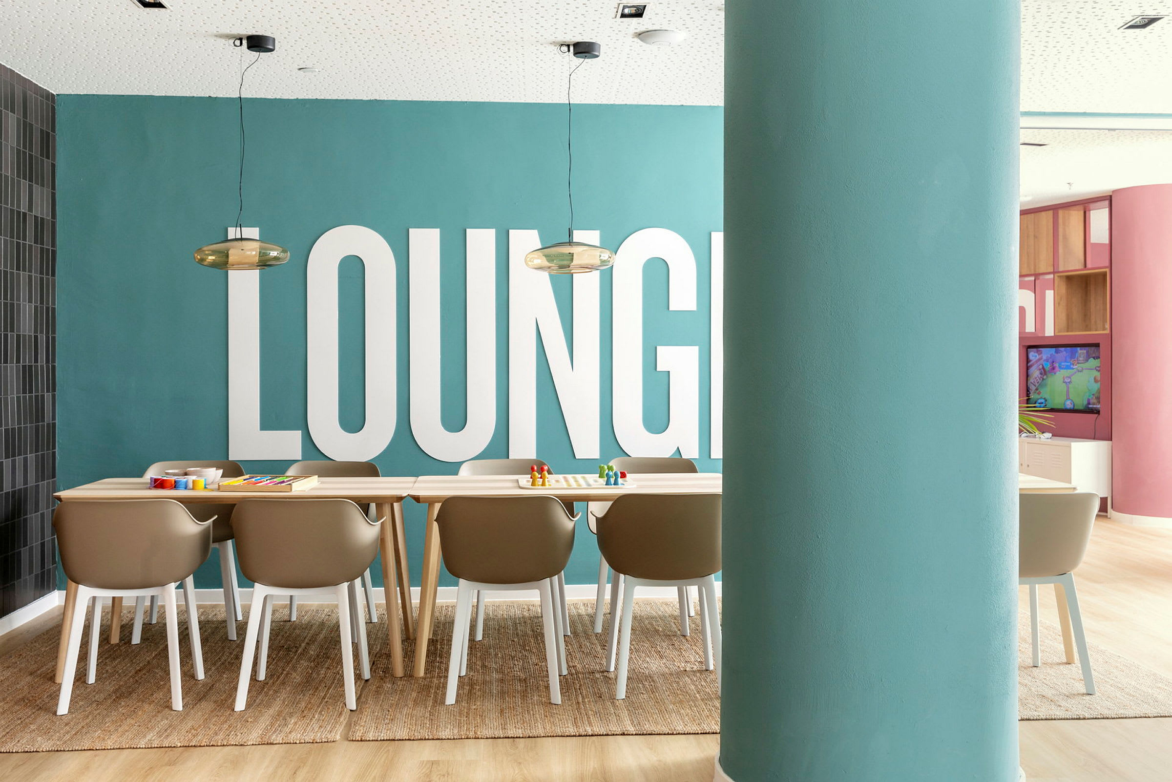Kuva huoneesta, jossa on matto, tuoleja ja pöytä sinisen seinän edessä, jossa lukee 'LOUNGE'. (Tekoälyn luoma teksti)