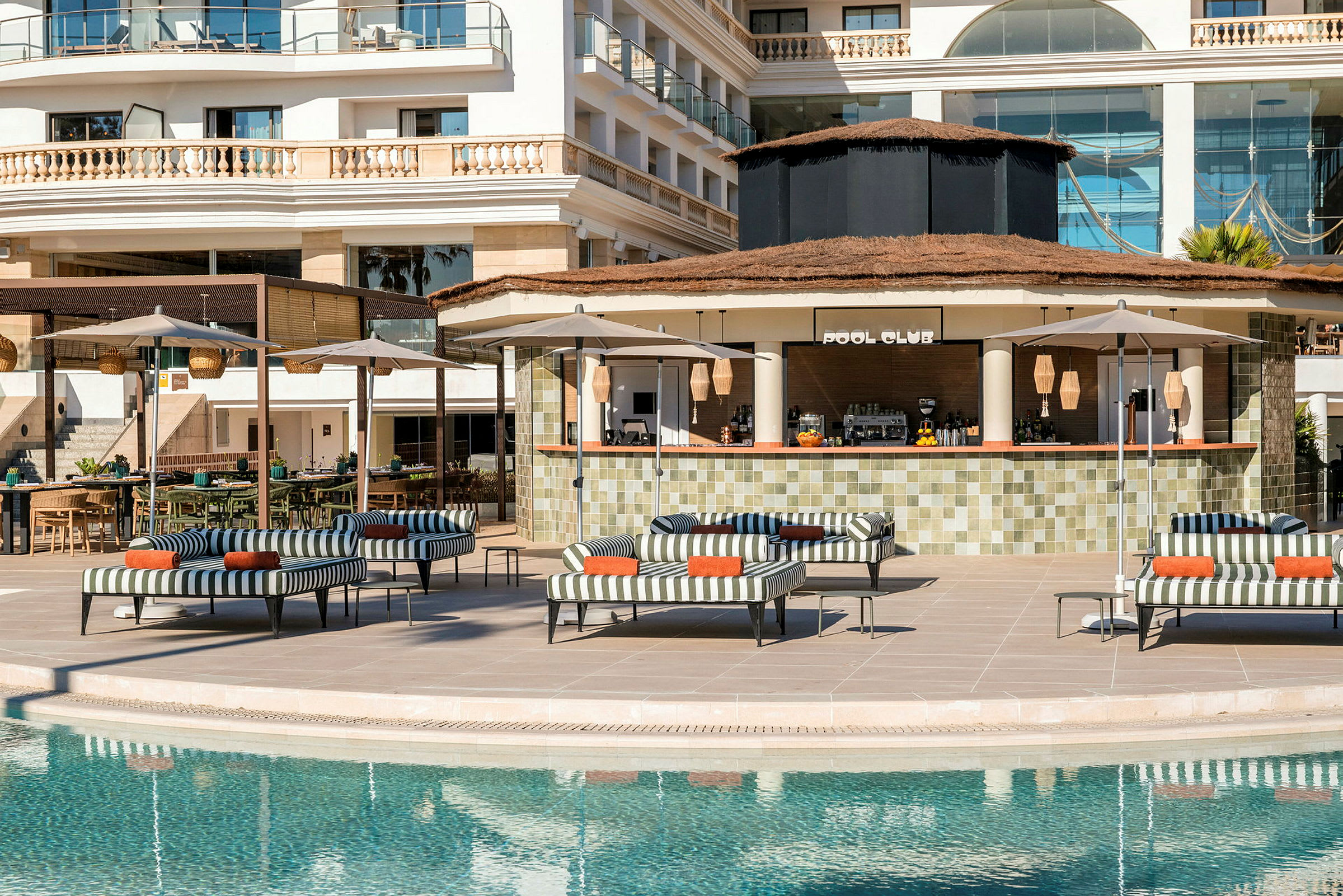 Uima-allas lepotuoleineen, aurinkovarjoineen ja taustalla oleva baari kyltillä "Pool Club". (Tekoälyn luoma teksti)