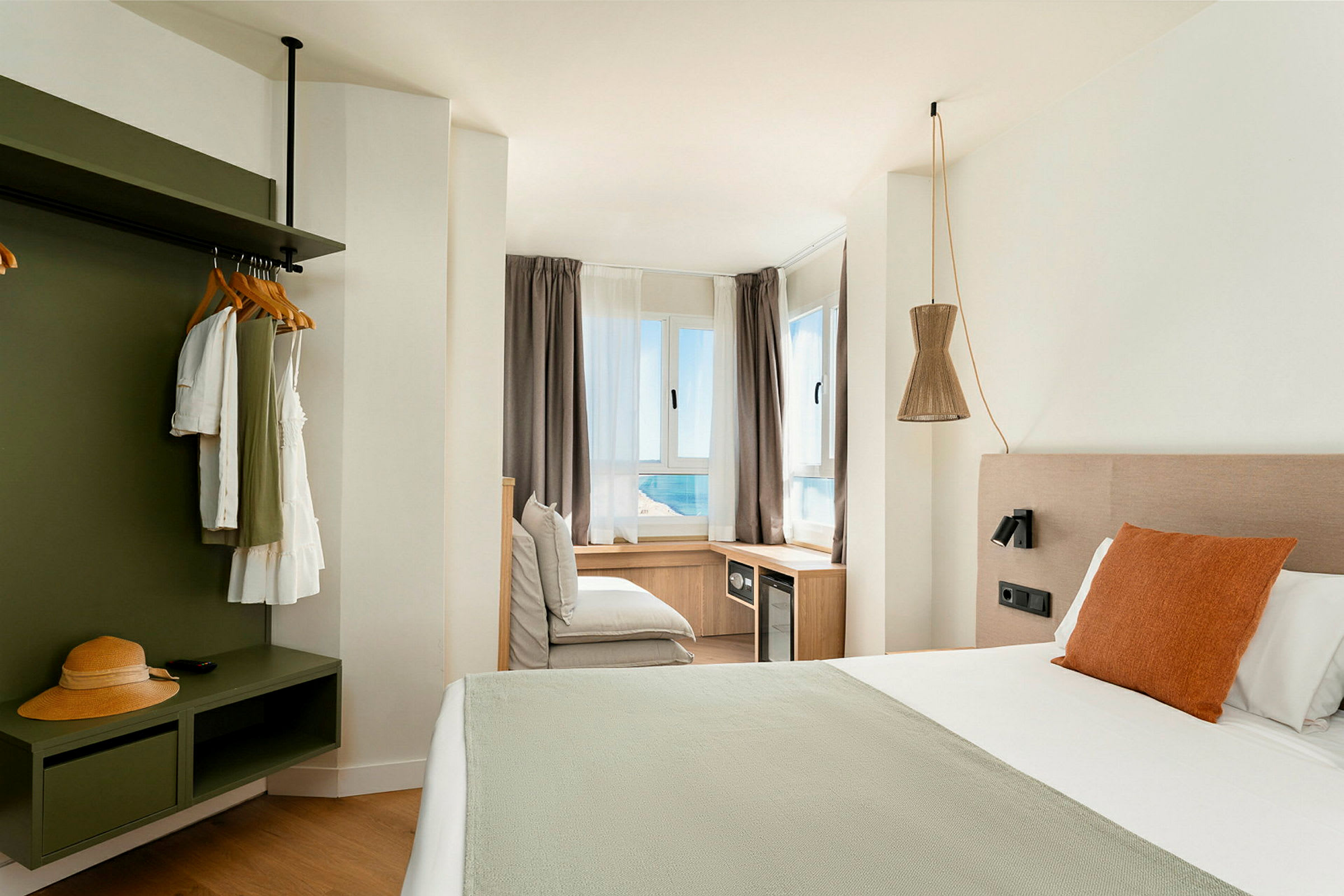 Valoisa ja moderni hotellihuone, jossa suuri sänky ja näkymä merelle ikkunoista. (Tekoälyn luoma teksti)
