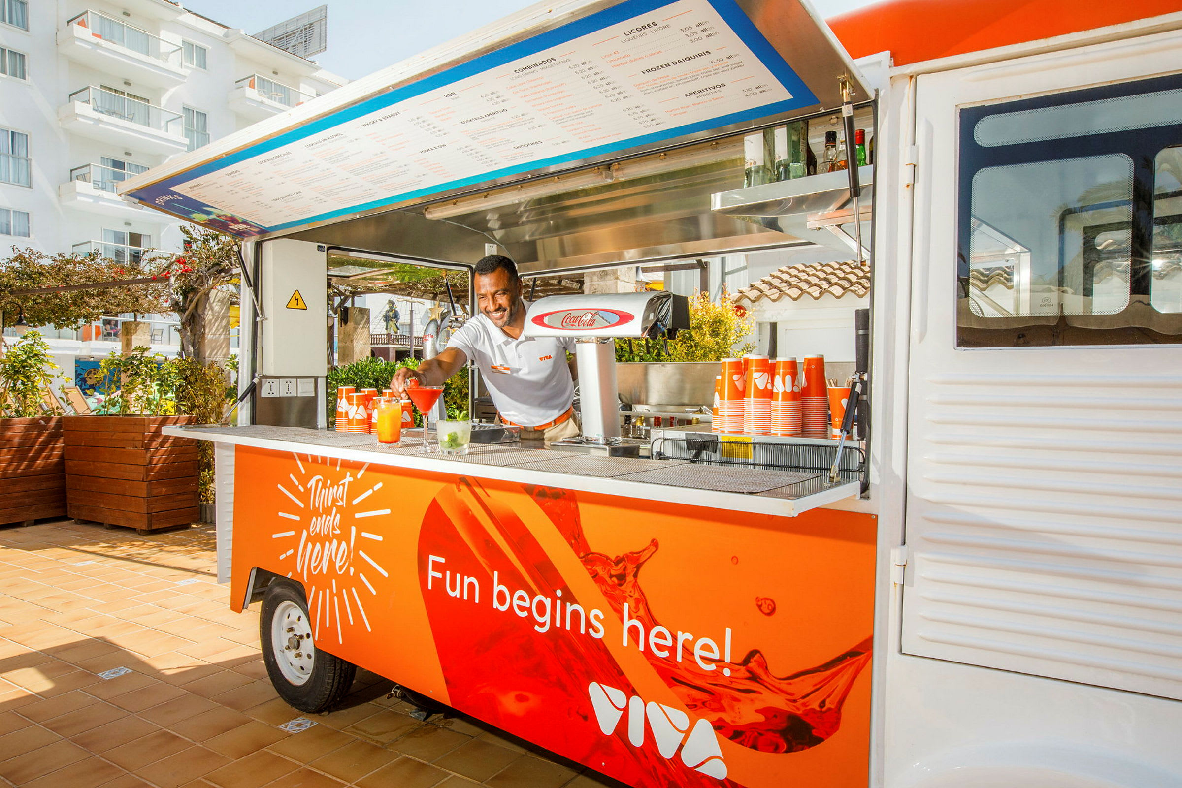 Liikkuva juomabaari oranssilla designilla ja tekstillä 'Fun begins here!'. (Tekoälyn luoma teksti)