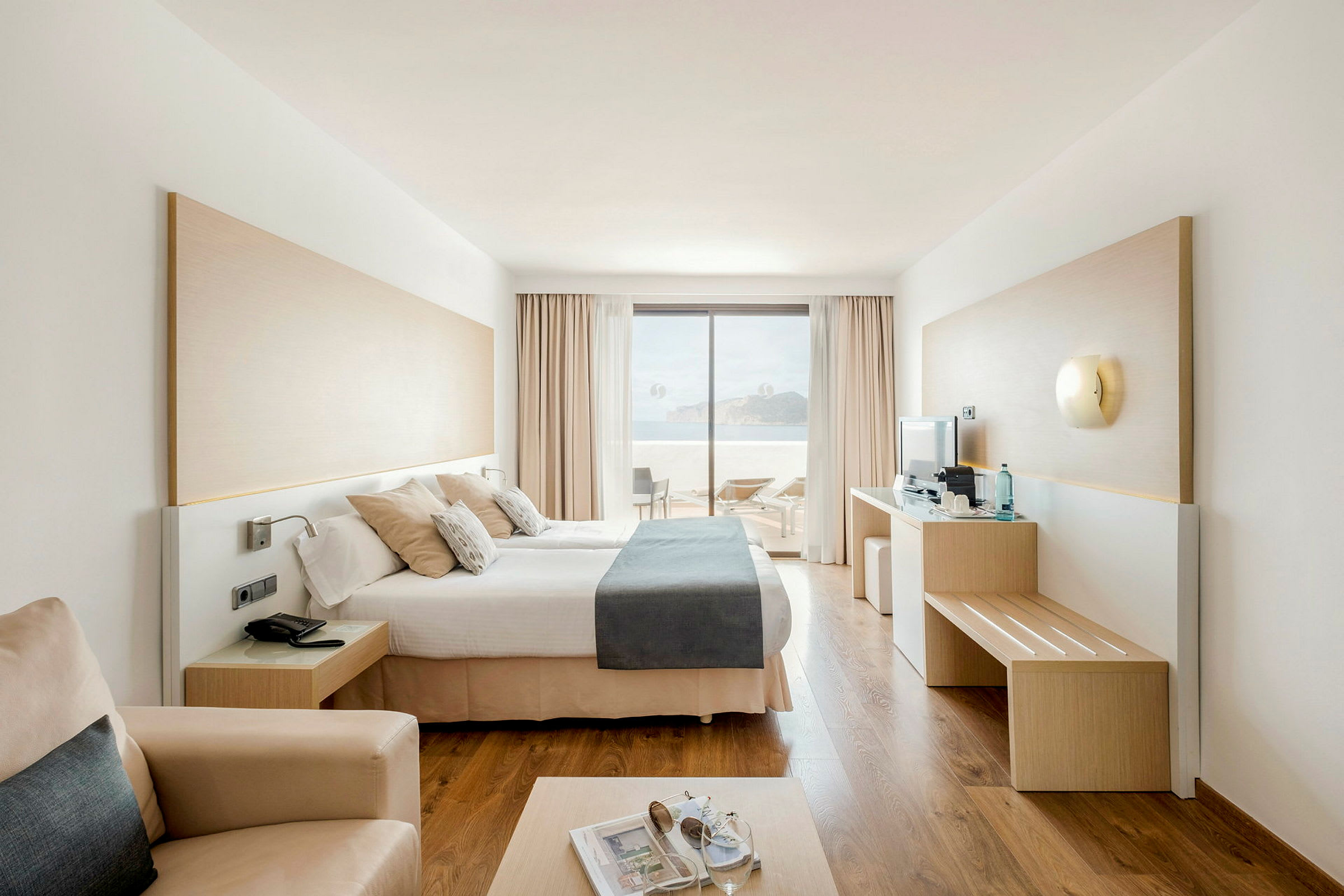 Moderni hotellihuone parivuoteella, näkymä terassille ja merelle. (Tekoälyn luoma teksti)