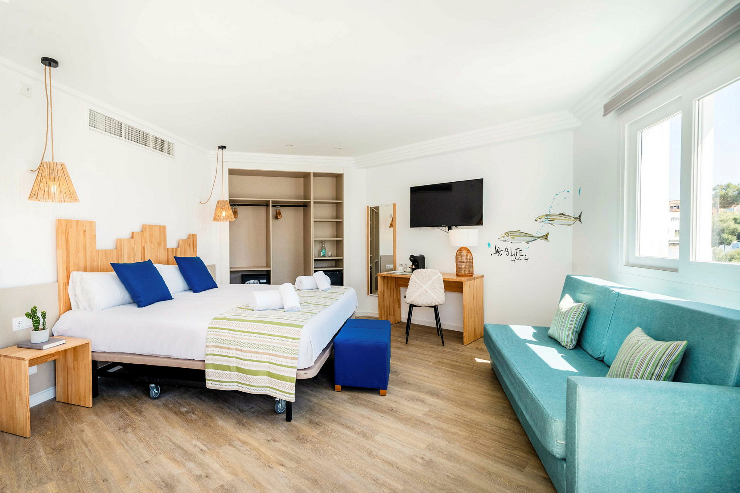 Valoisa hotellihuone, jossa on parivuode, sohva ja kirjoituspöytä. (Tekoälyn luoma teksti)