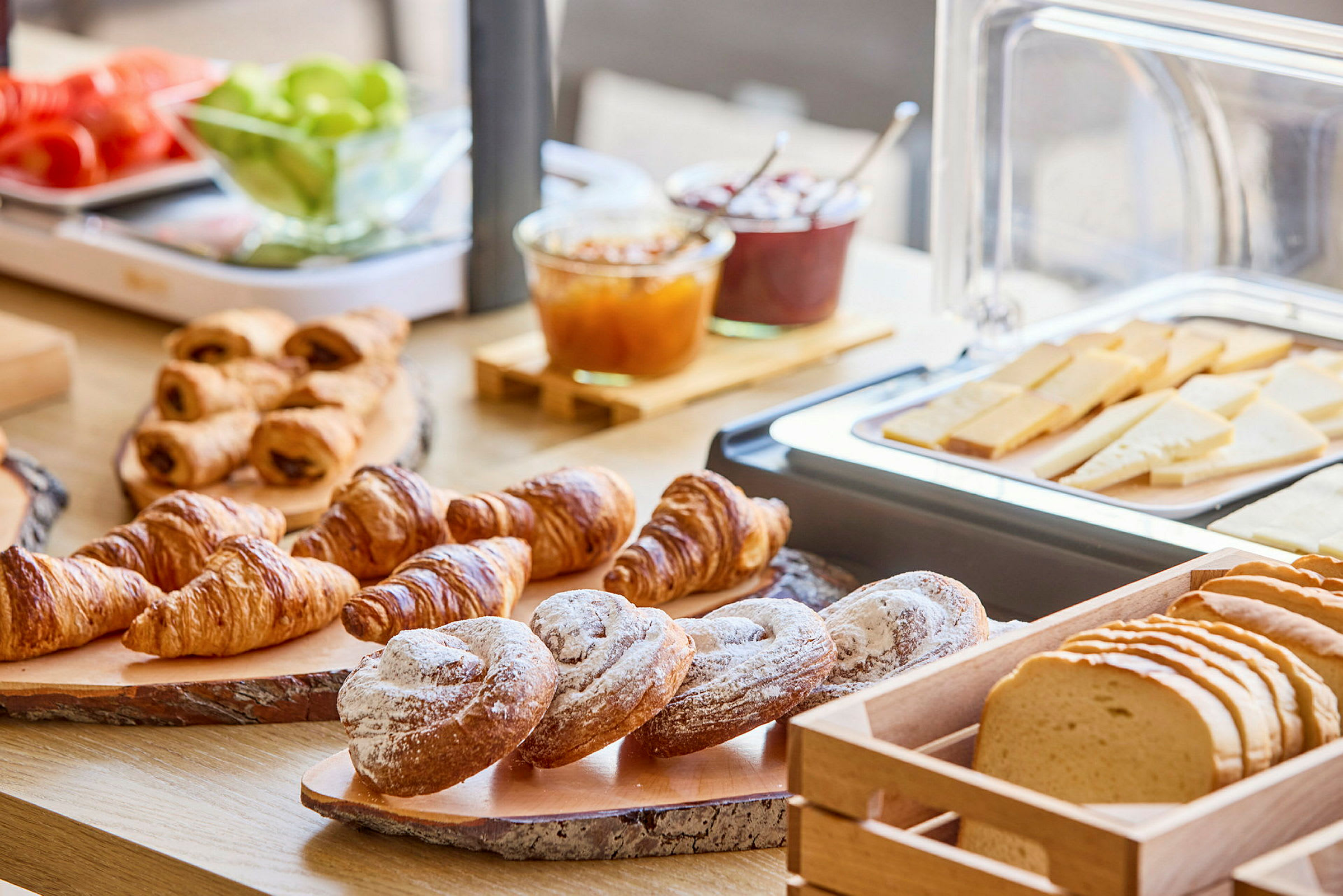 Aamiaispöytä, jossa on croissanteja, leipää ja juustoviipaleita. (Tekoälyn luoma teksti)