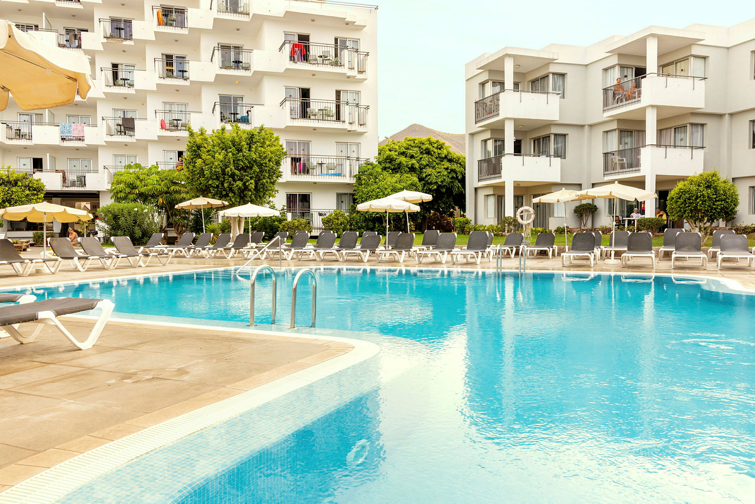 Hotellirakennus parvekkeineen suuren ulkouima-altaan vieressä. (Tekoälyn luoma teksti)
