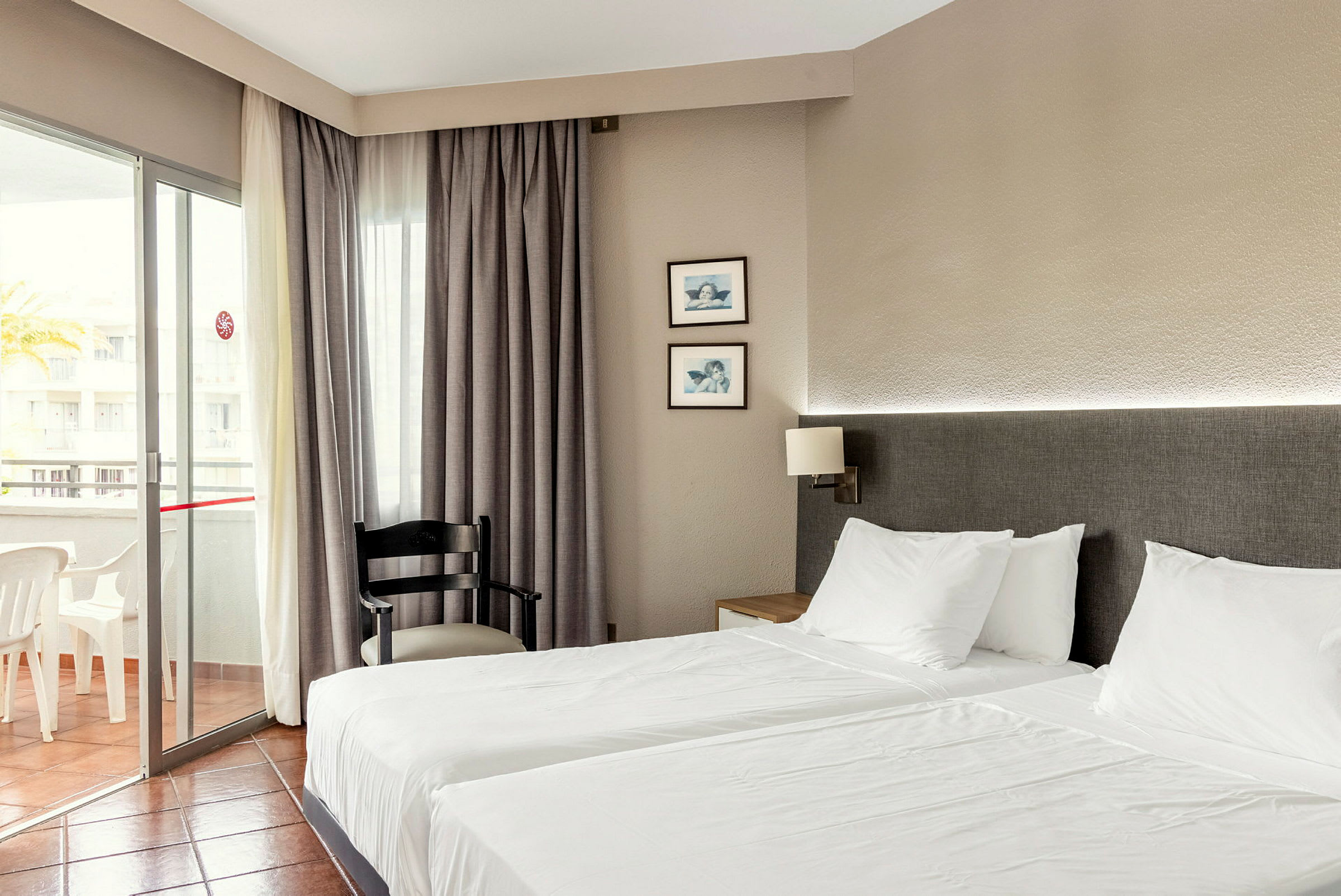 Hotellihuone, jossa kaksi erillistä sänkyä, tuoli ja parveke. (Tekoälyn luoma teksti)