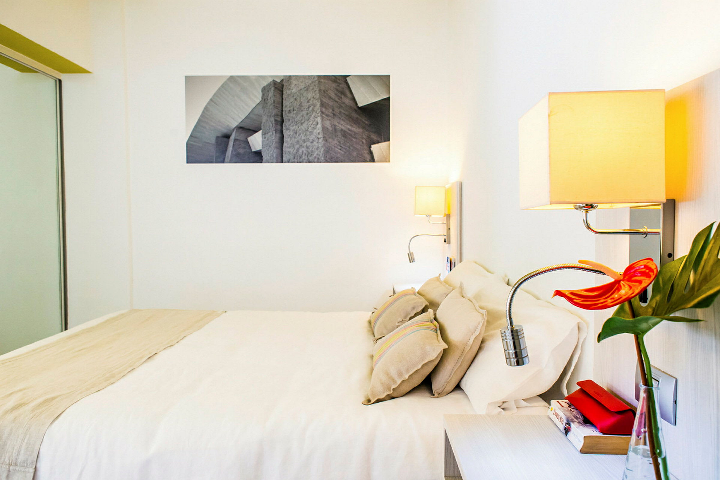 Hotellihuone, jossa on parivuode, vaaleat seinät, moderni sisustus ja seinälamppu. (Tekoälyn luoma teksti)