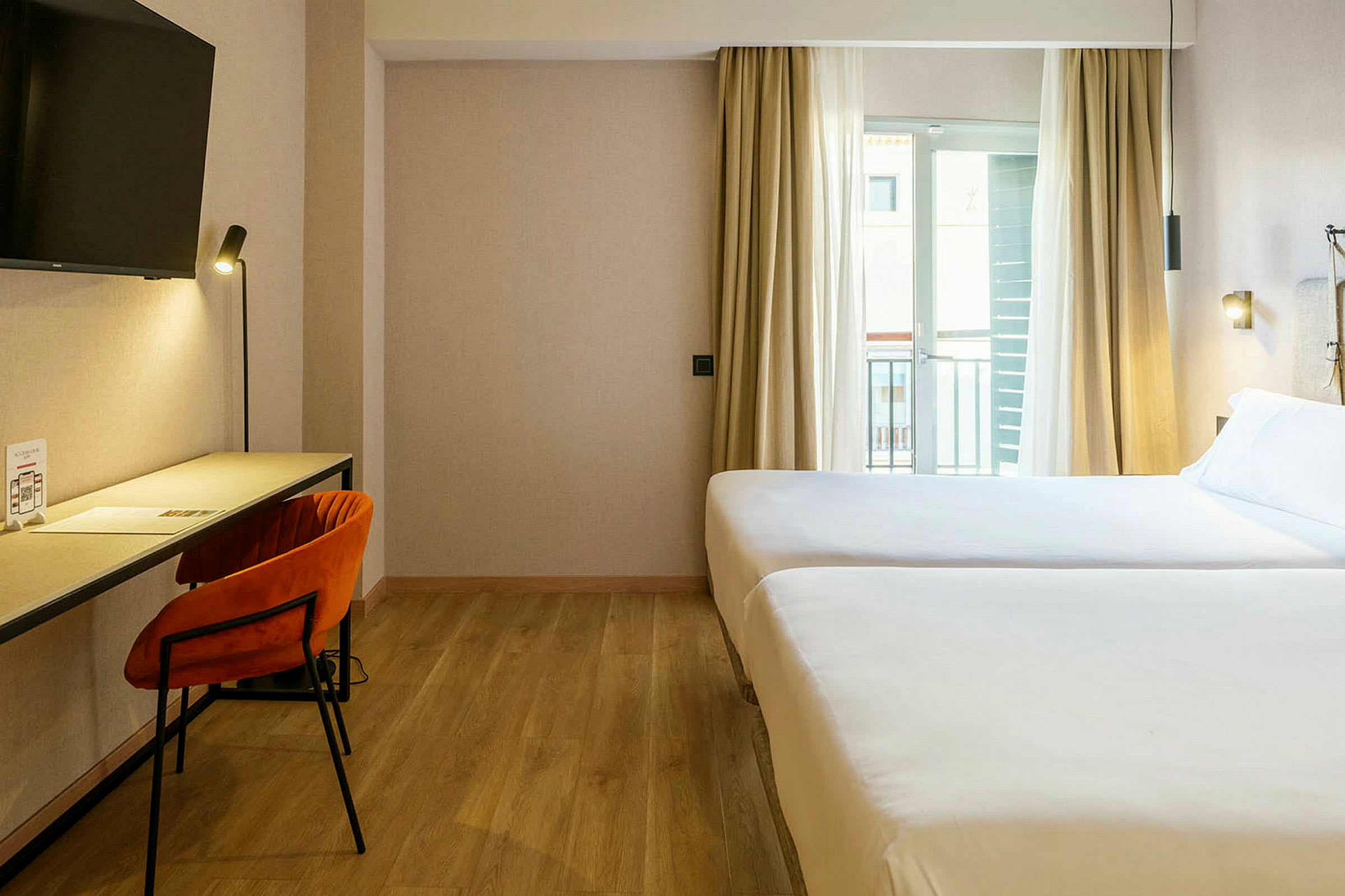 Hotellihuone, jossa on kaksi sänkyä, kirjoituspöytä ja tuoli. (Tekoälyn luoma teksti)