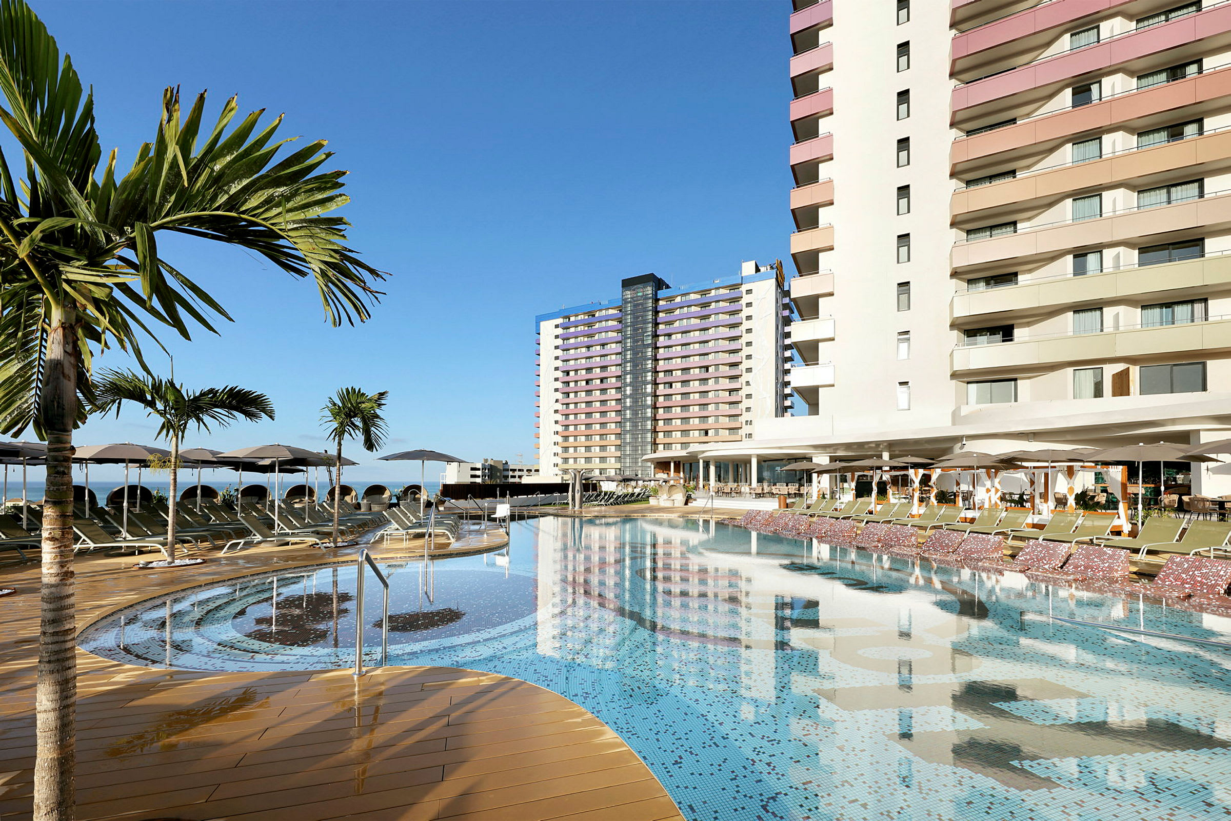 Ulkoallas hotellissa, jossa on palmuja ja nojatuoleja. (Tekoälyn luoma teksti)