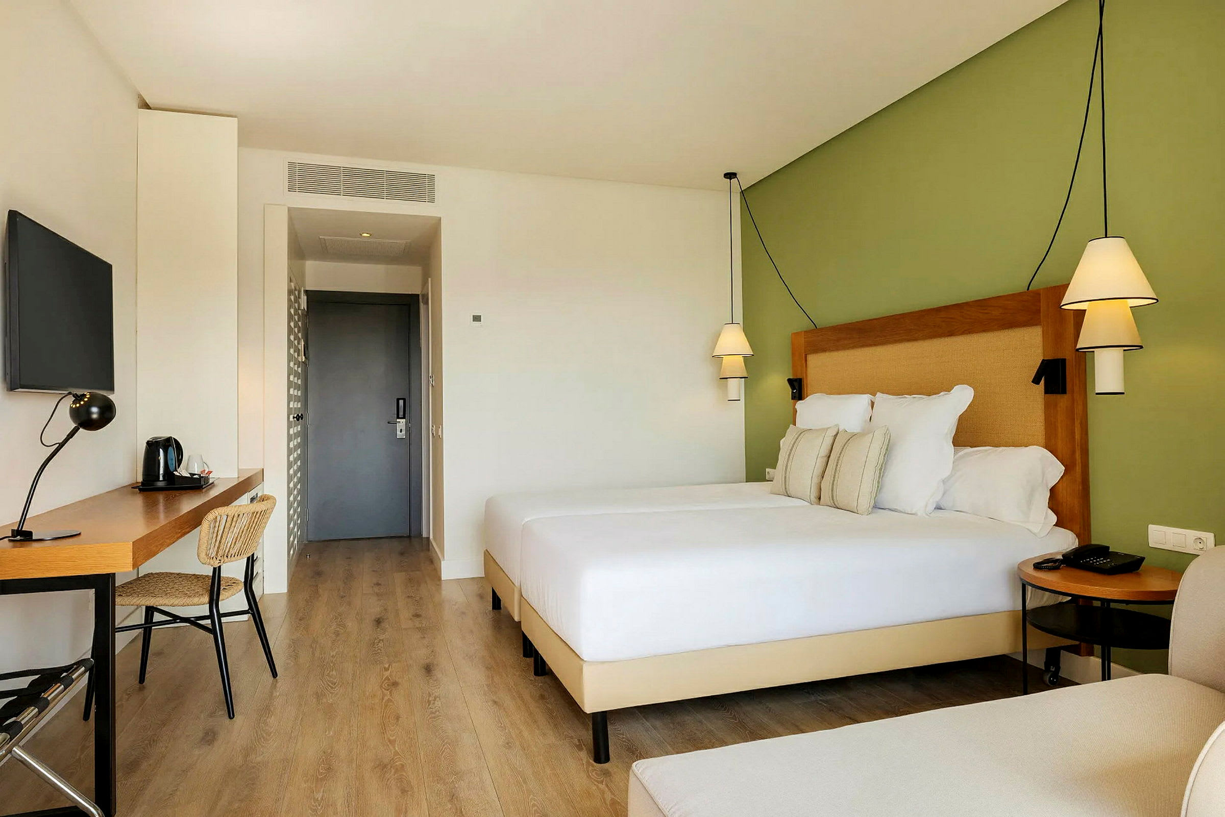 Moderni hotellihuone, jossa on parivuode, kirjoituspöytä ja tuoli. (Tekoälyn luoma teksti)