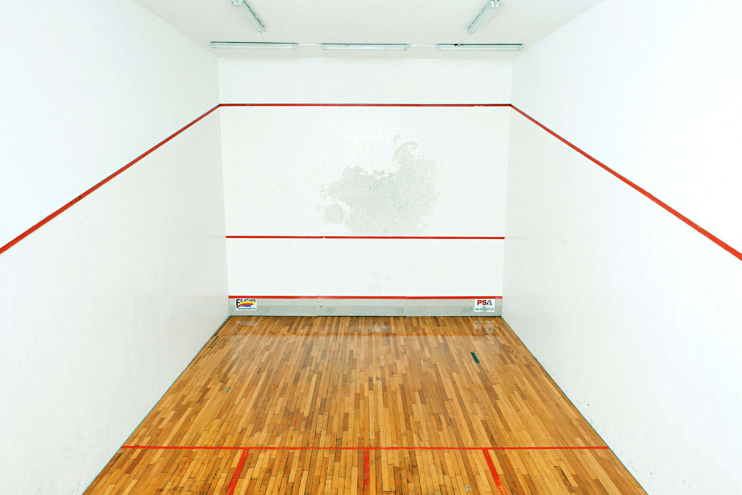 Kuva squashkentästä, jossa on puulattia ja valkoiset seinät, merkittynä punaisilla viivoilla. (Tekoälyn luoma teksti)