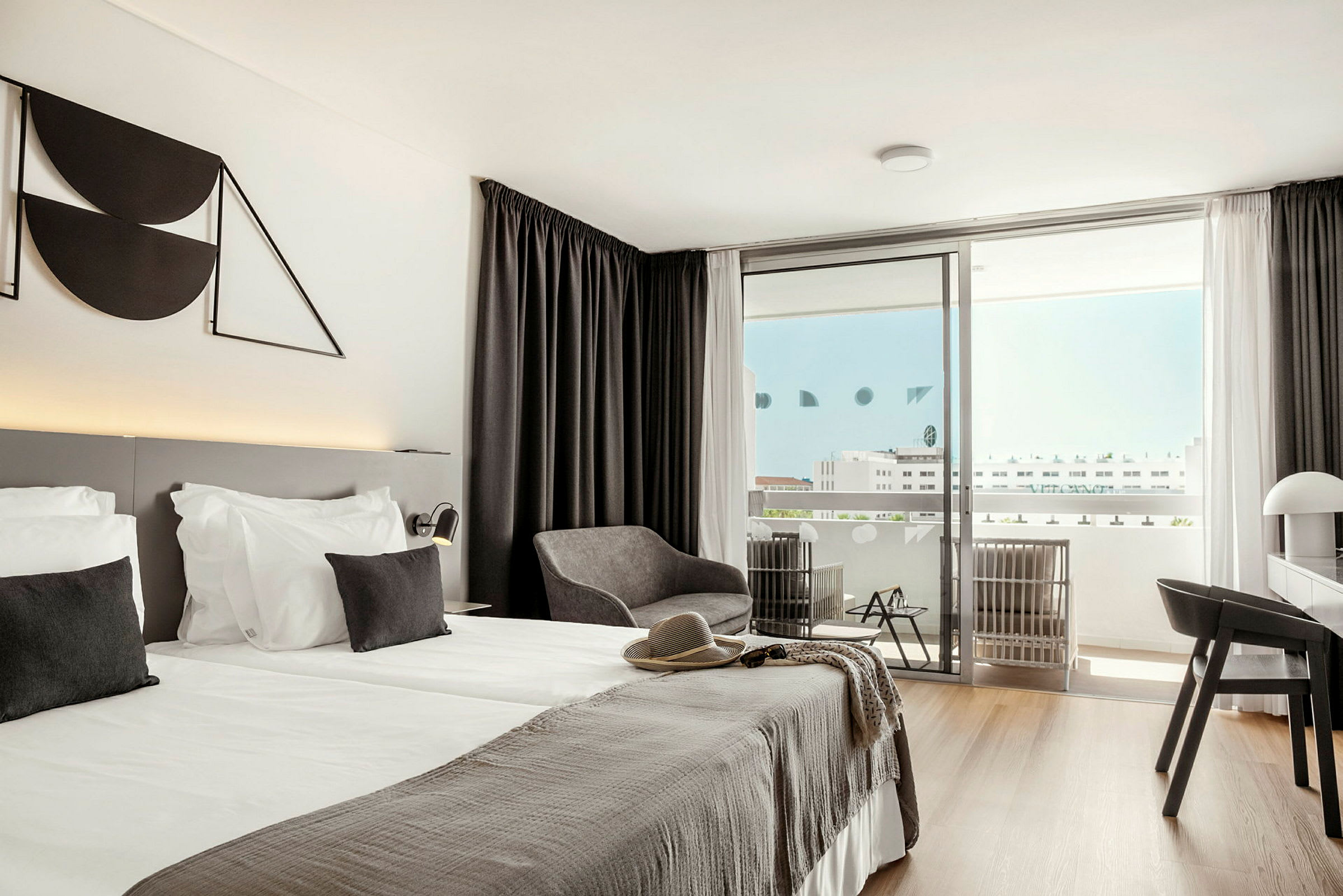 Moderni hotellihuone, jossa parivuode, oleskelutila ja parveke. (Tekoälyn luoma teksti)