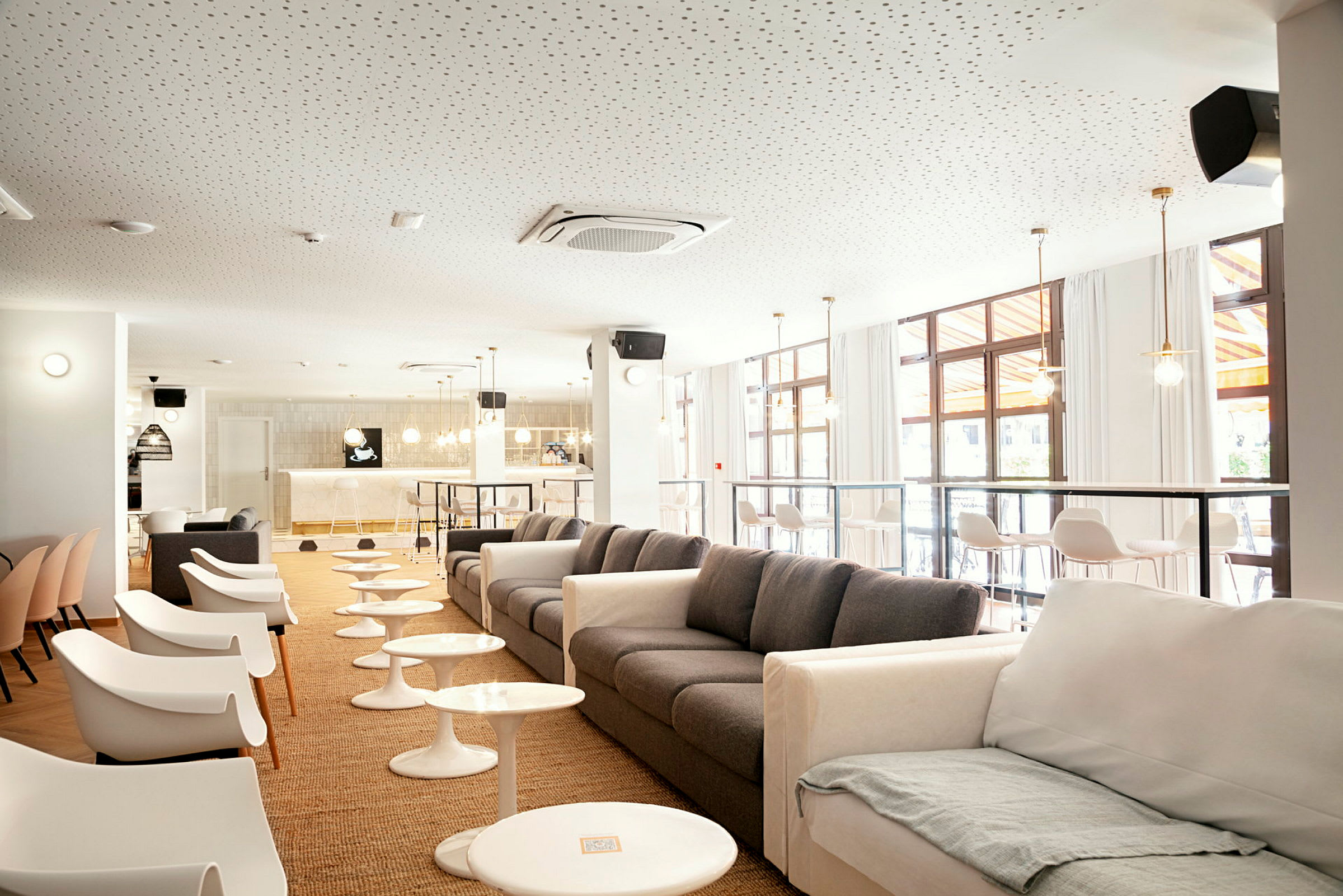 Moderni lounge, jossa on sohvia ja tuoleja, pieniä pöytiä ja baari taustalla. (Tekoälyn luoma teksti)