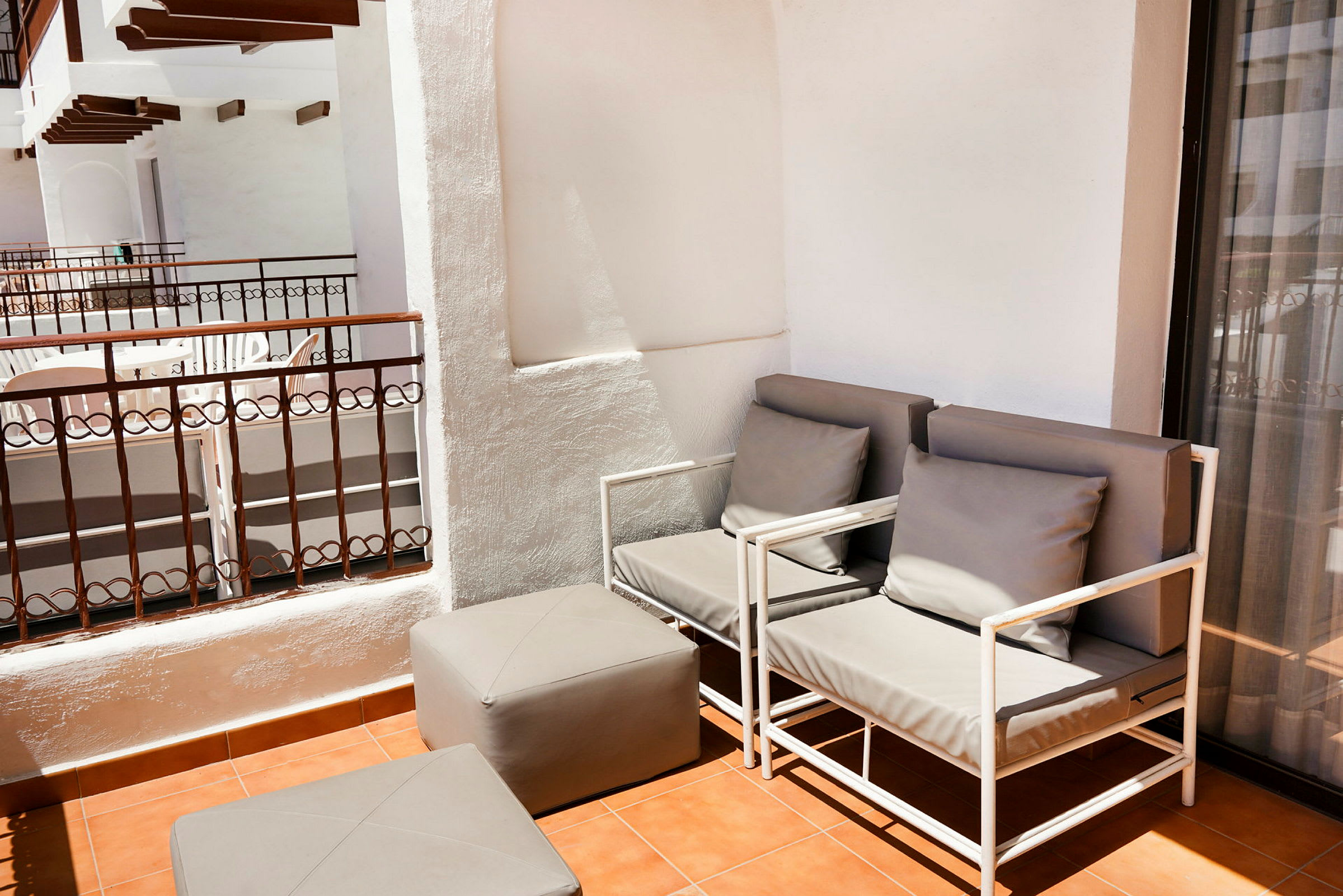 Terassi, jossa kaksi harmaata istuinhuonekalua ja yhteensopiva jalkajakkara terrakottalaattalattialla. (Tekoälyn luoma teksti)