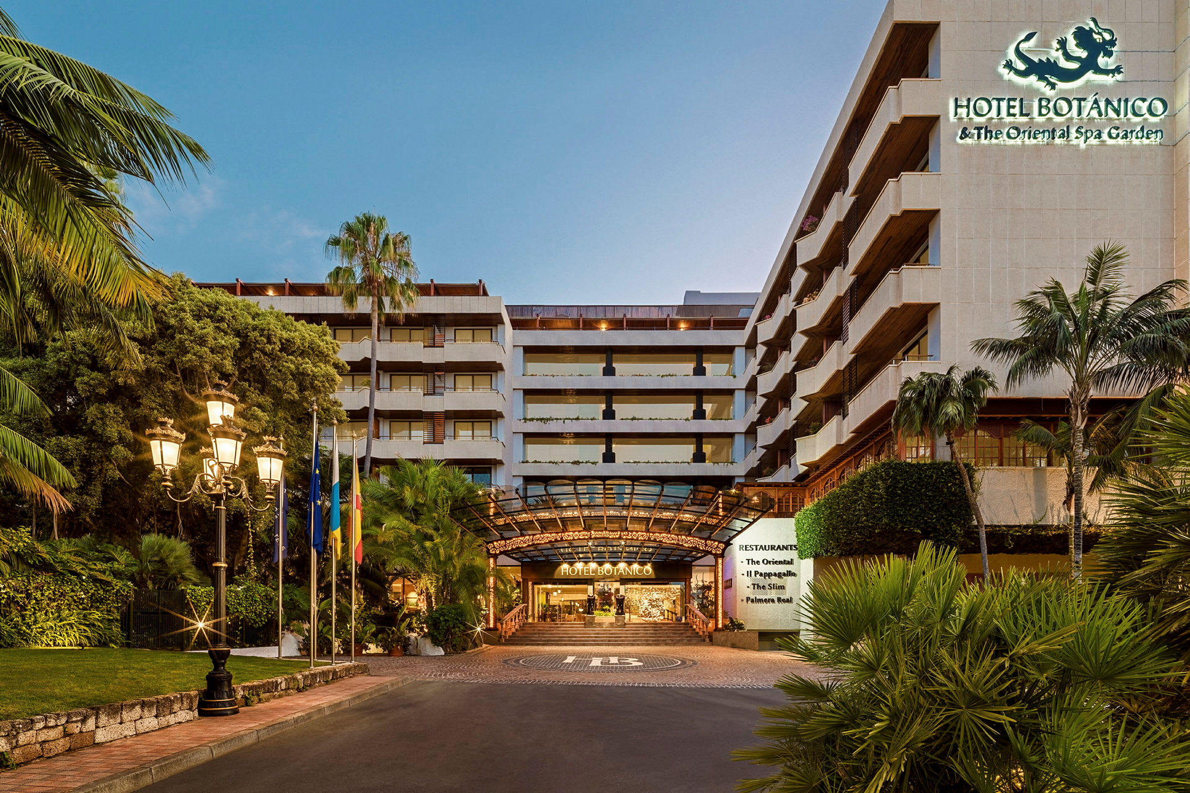 Hotel Botanicon sisäänkäynti, jota ympäröivät trooppiset kasvit ja katuvalot. (Tekoälyn luoma teksti)