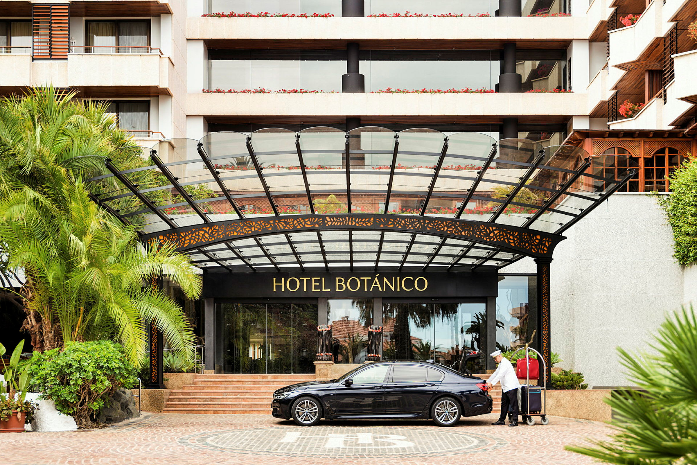Hotel Botánicon sisäänkäynti, jossa on auto ja matkatavaravaunu. (Tekoälyn luoma teksti)