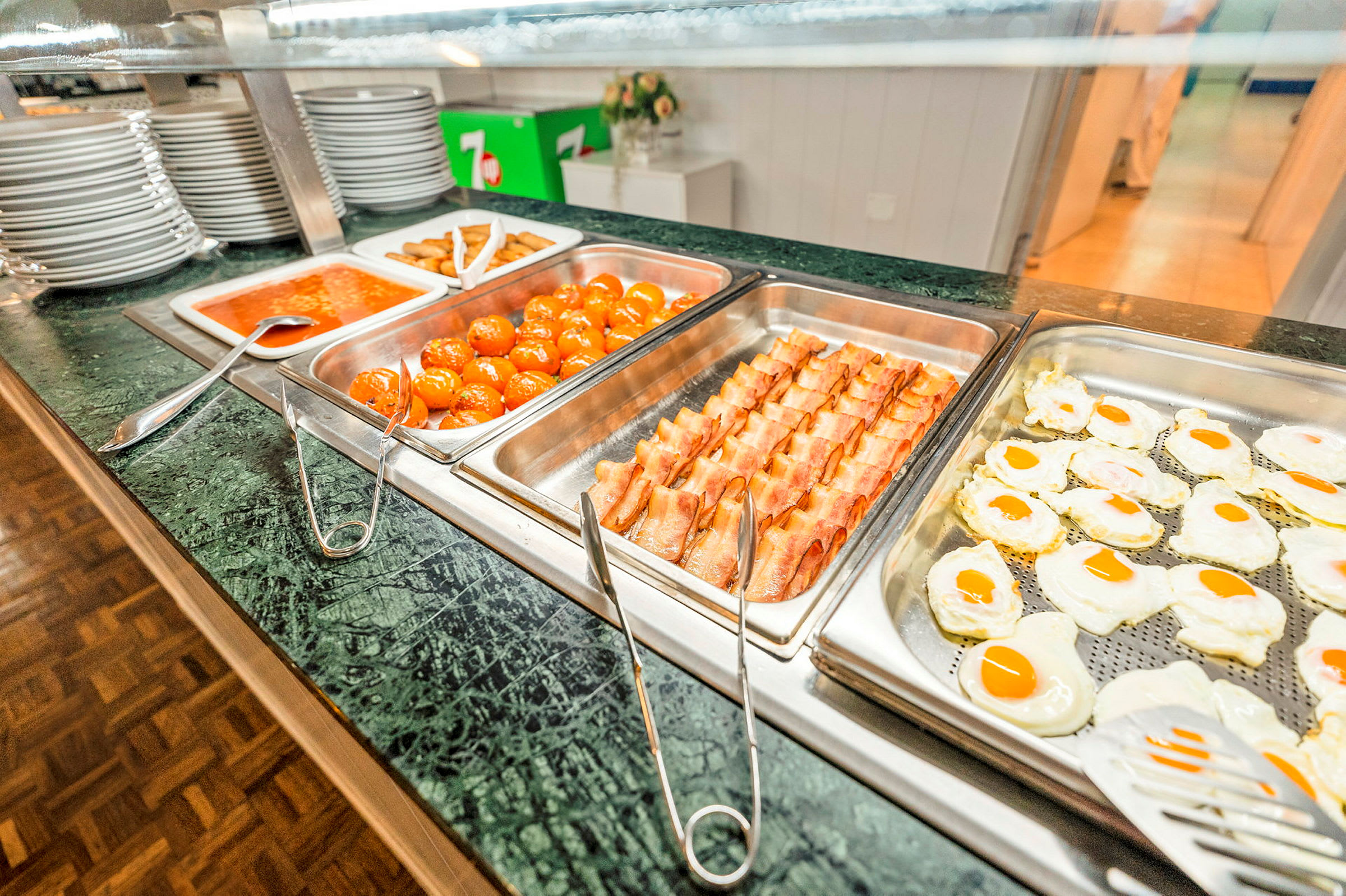 Buffetpalvelu, jossa eri ruokia, kuten paistettuja munia, pekonia, lihapullia ja tomaattikastiketta. (Tekoälyn luoma teksti)