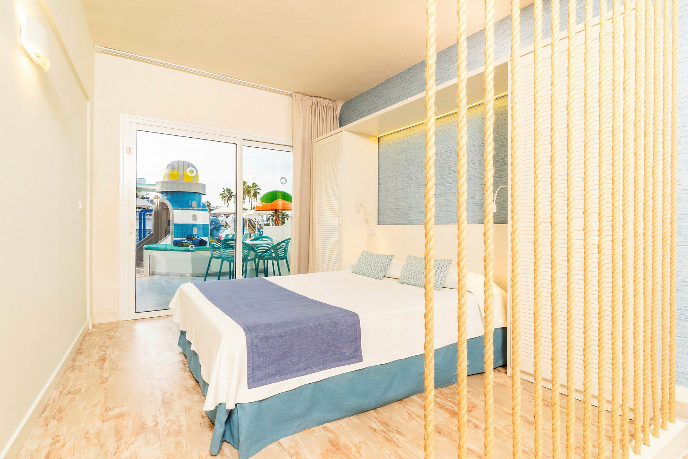 Hotellihuone, jossa vaaleat sisustuselementit ja näkymä altaalle ja leikkipaikalle. (Tekoälyn luoma teksti)