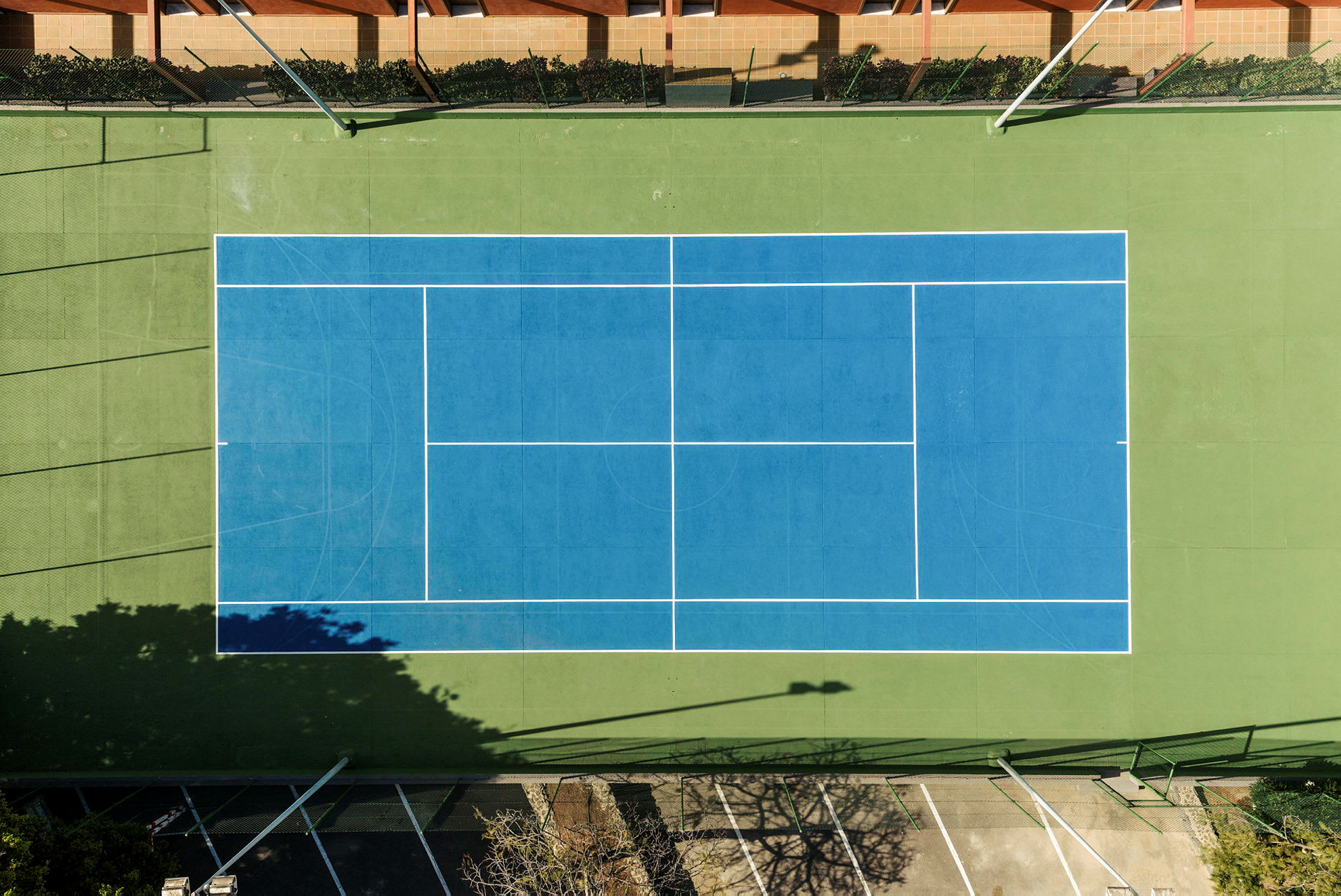Lintuperspektiivistä otettu kuva tenniskentästä, jossa on sininen kenttä ja vihreät reunat. (Tekoälyn luoma teksti)