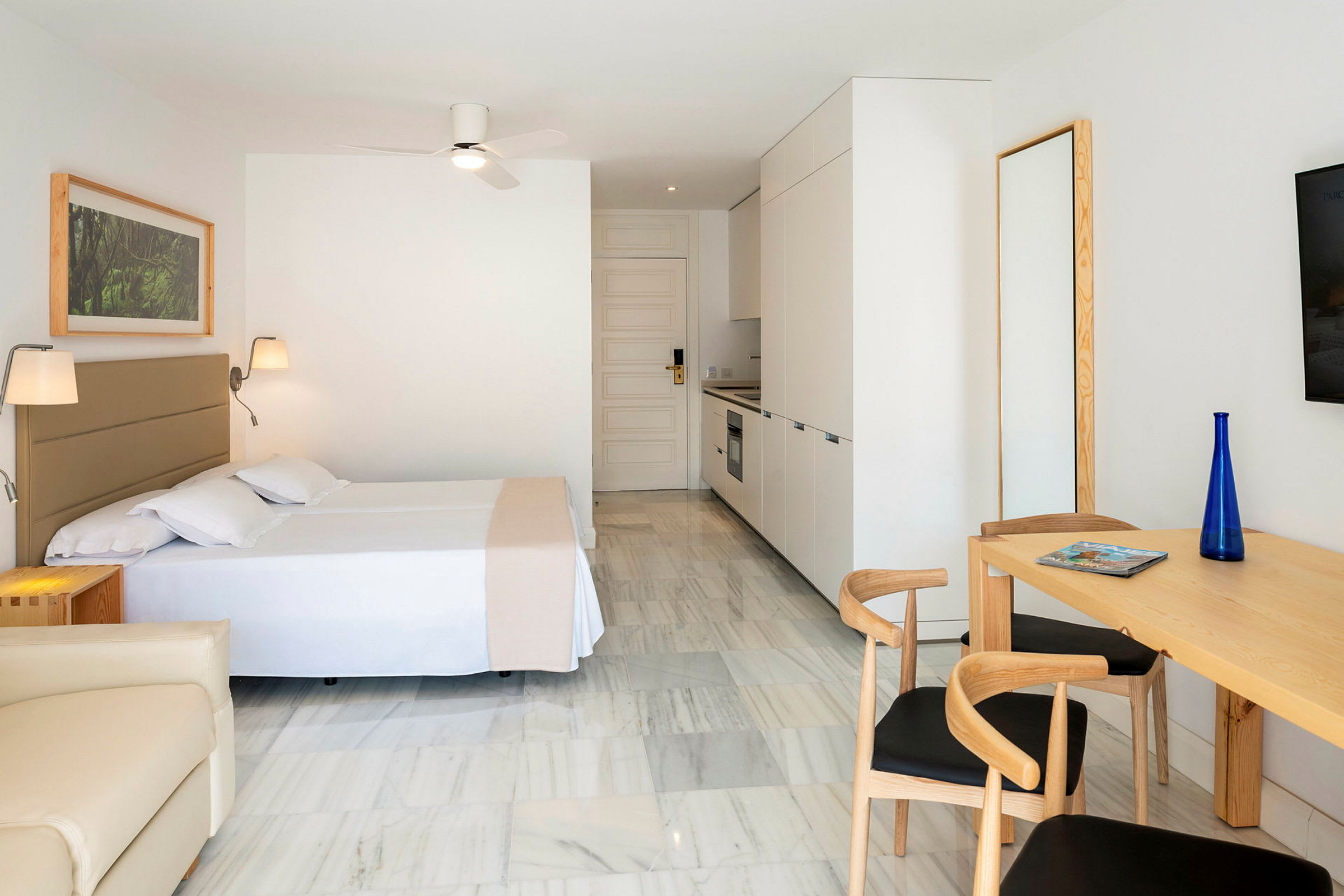 Modernisti sisustettu hotellihuone keittiönurkalla ja ruokapöydällä. (Tekoälyn luoma teksti)